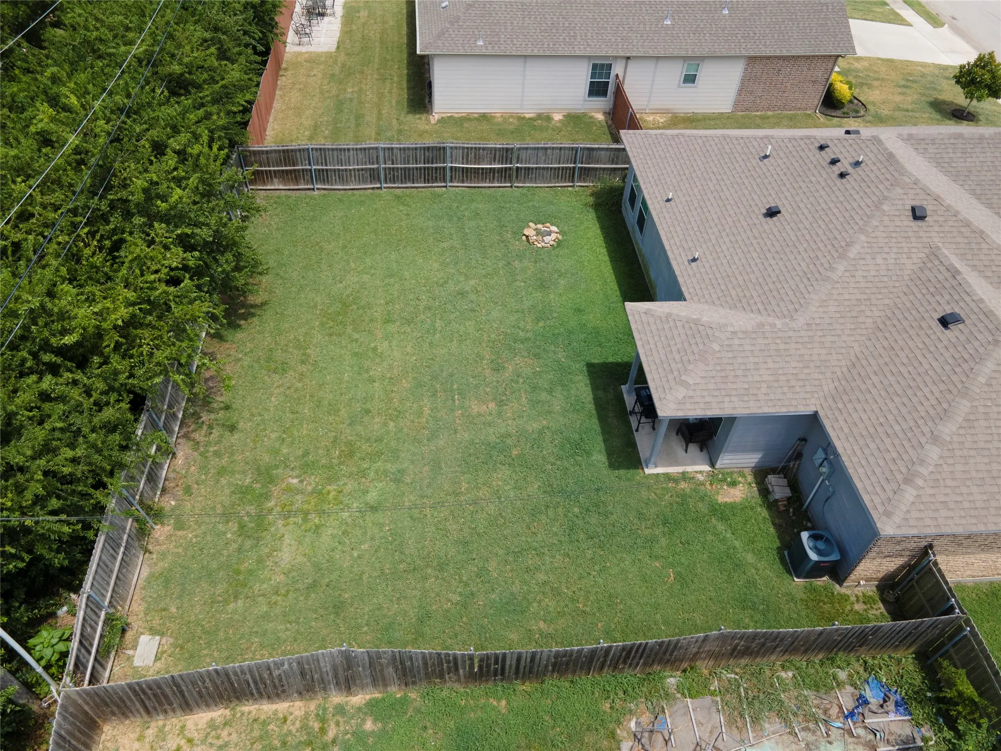 Expansive fenced backyard featuring a substantial lawn area and a covered patio