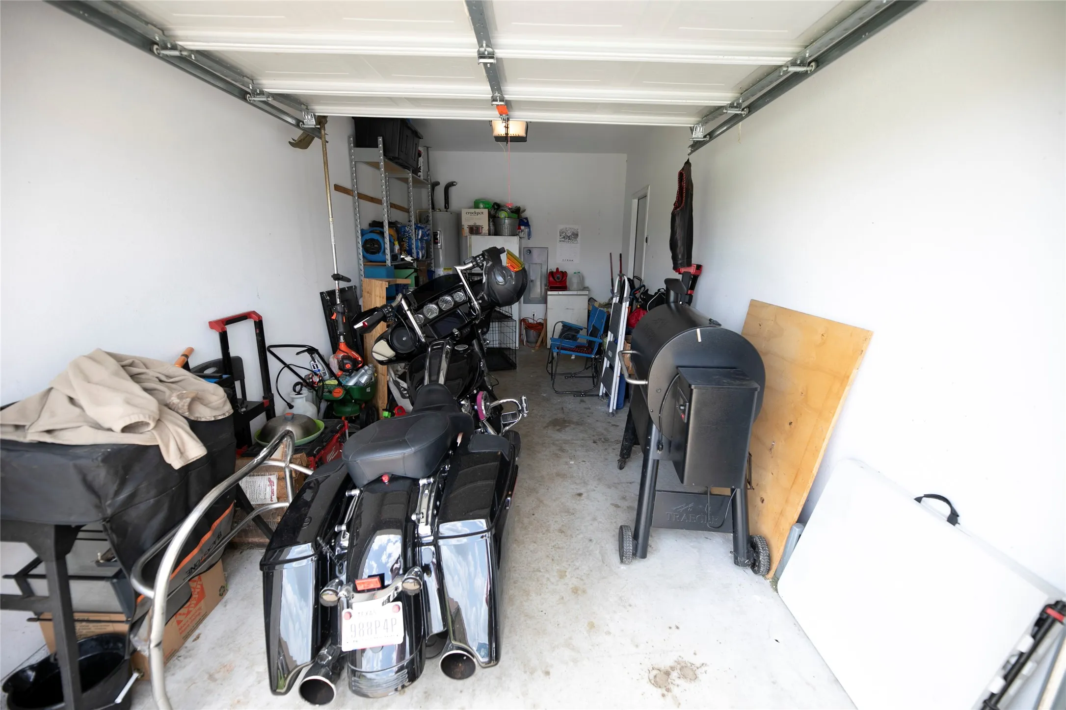 Single-car garage with concrete flooring, white painted walls, and an overhead garage door with track system