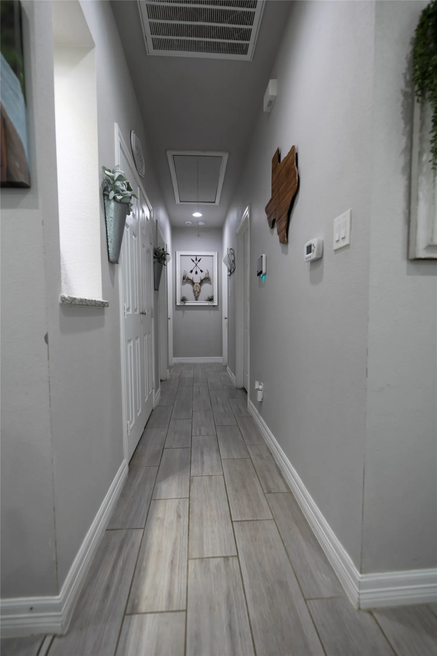 Hallway featuring light-toned wood-finish flooring, white baseboards, and neutral wall tones