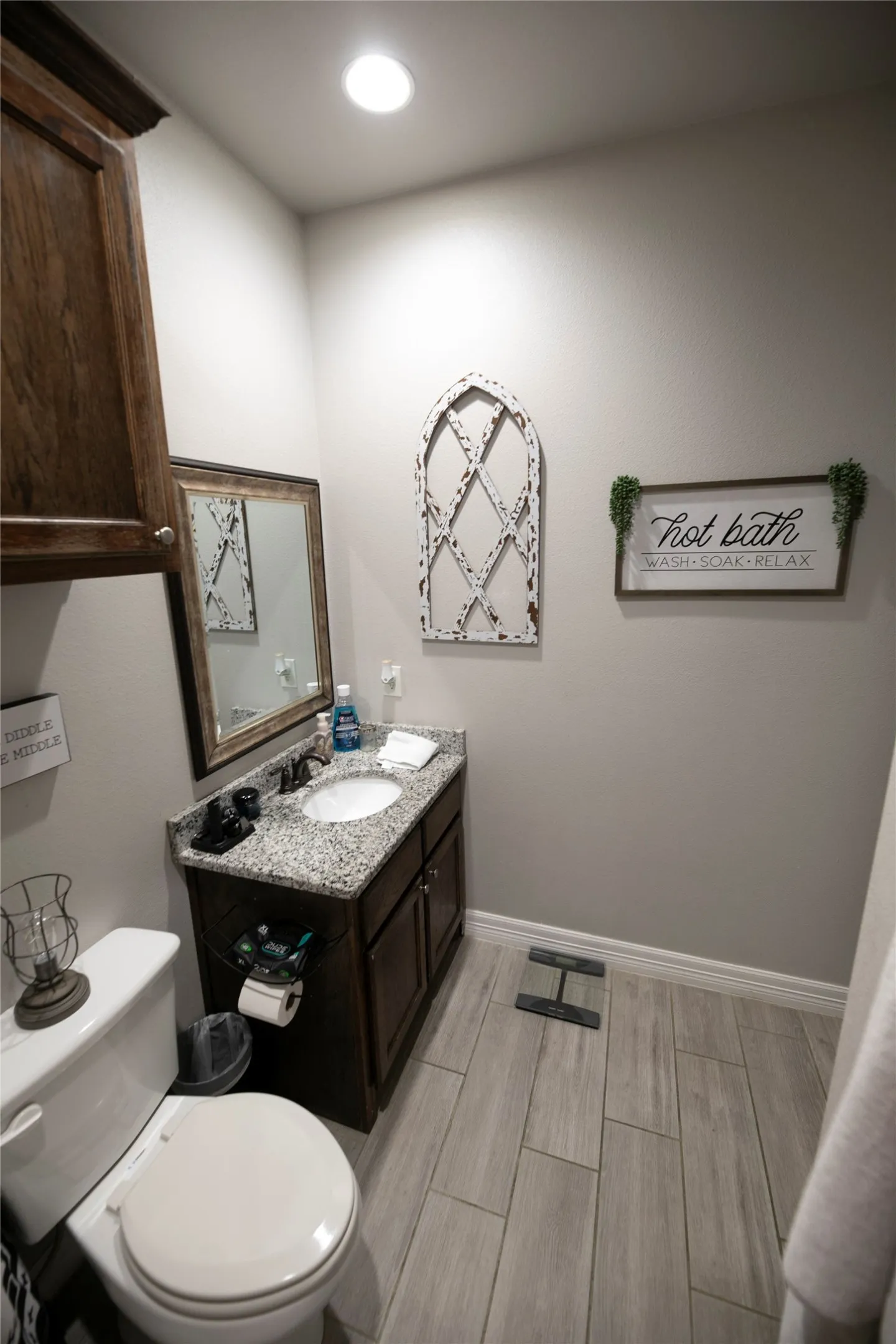 Bathroom featuring a single vanity with dark wood cabinetry, a granite countertop, and an undermount sink