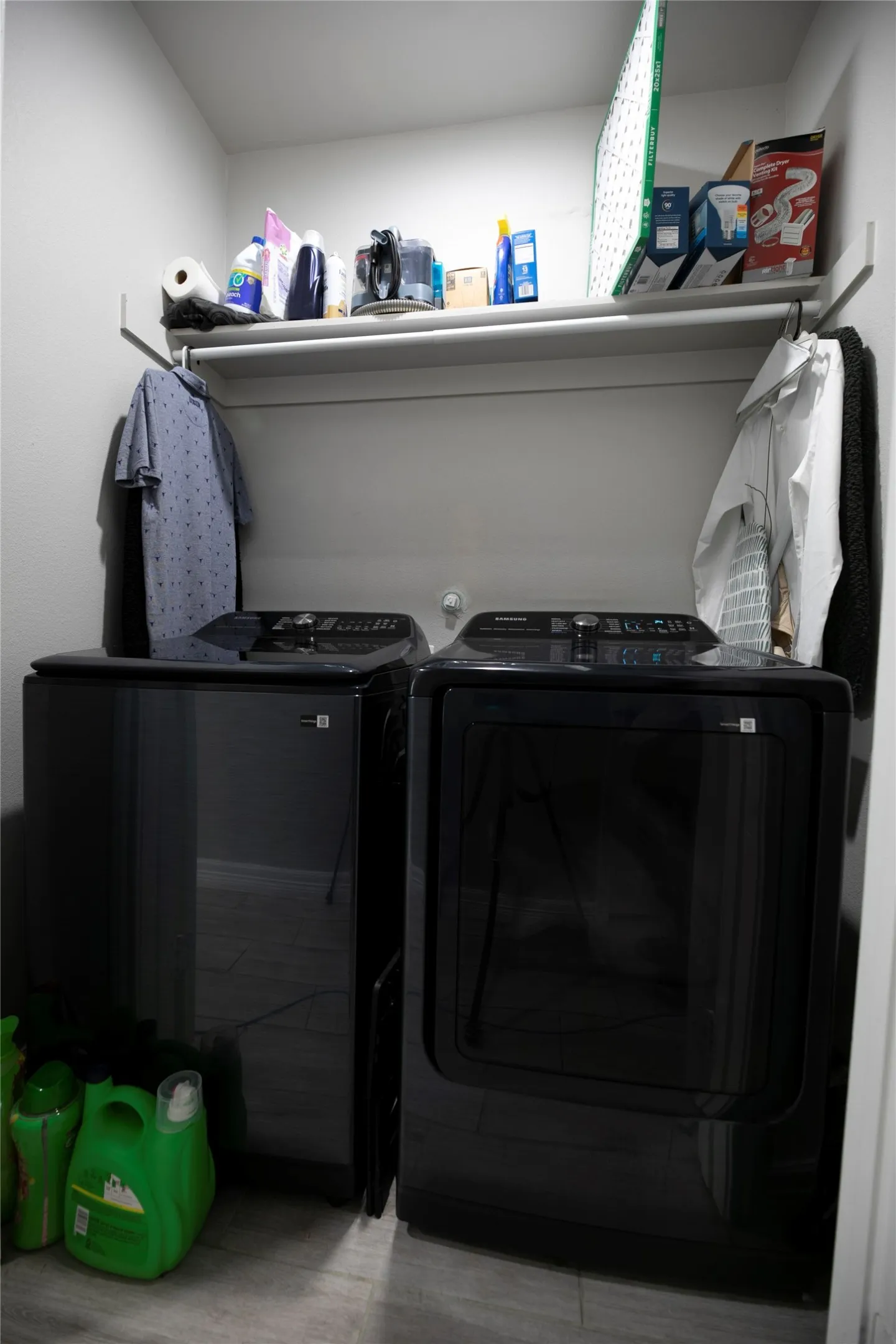 Dedicated laundry area featuring a washer and dryer, an overhead shelf, and a clothing rod