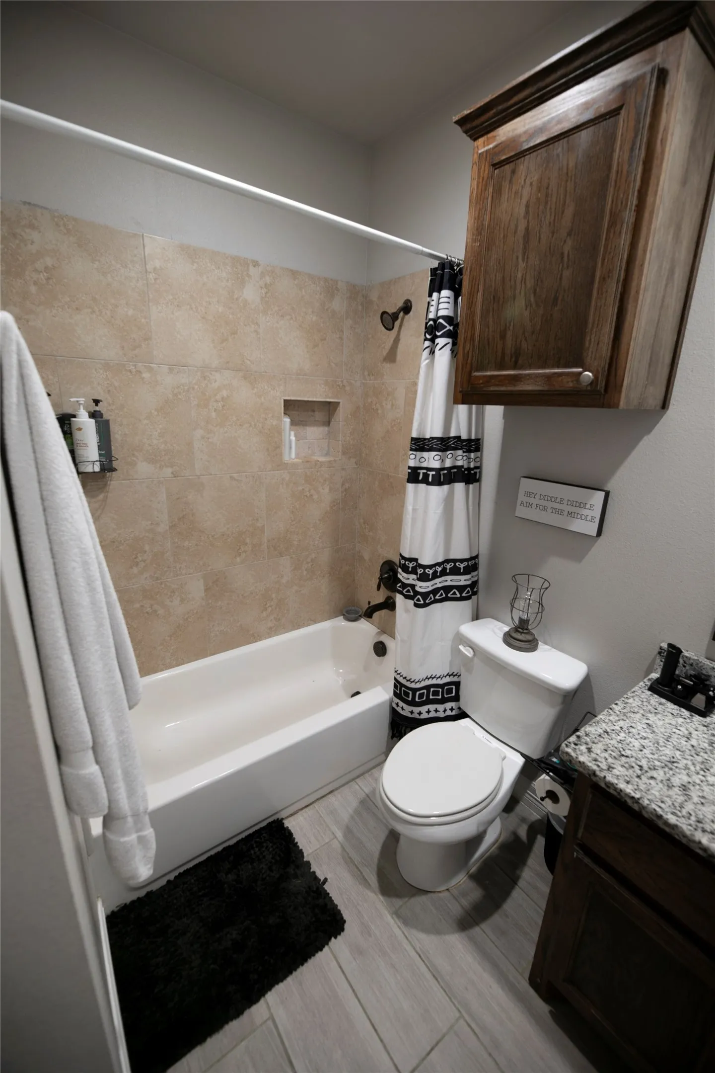 Bathroom featuring a white bathtub with tile surround, built-in shower niche, and dark bronze fixtures