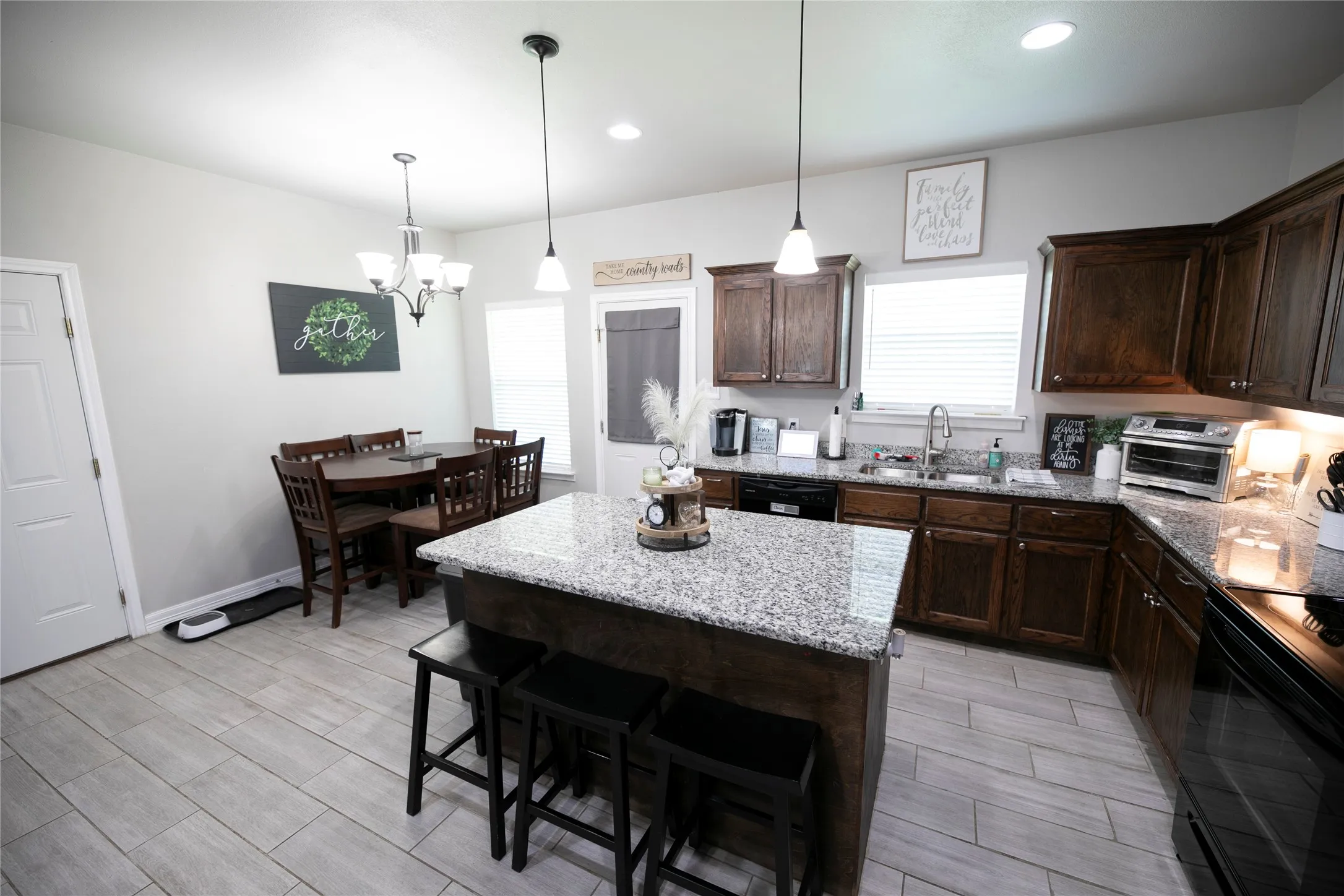 Open-concept kitchen featuring an island with granite countertops, dark wood-finish cabinetry, and light wood-finish flooring