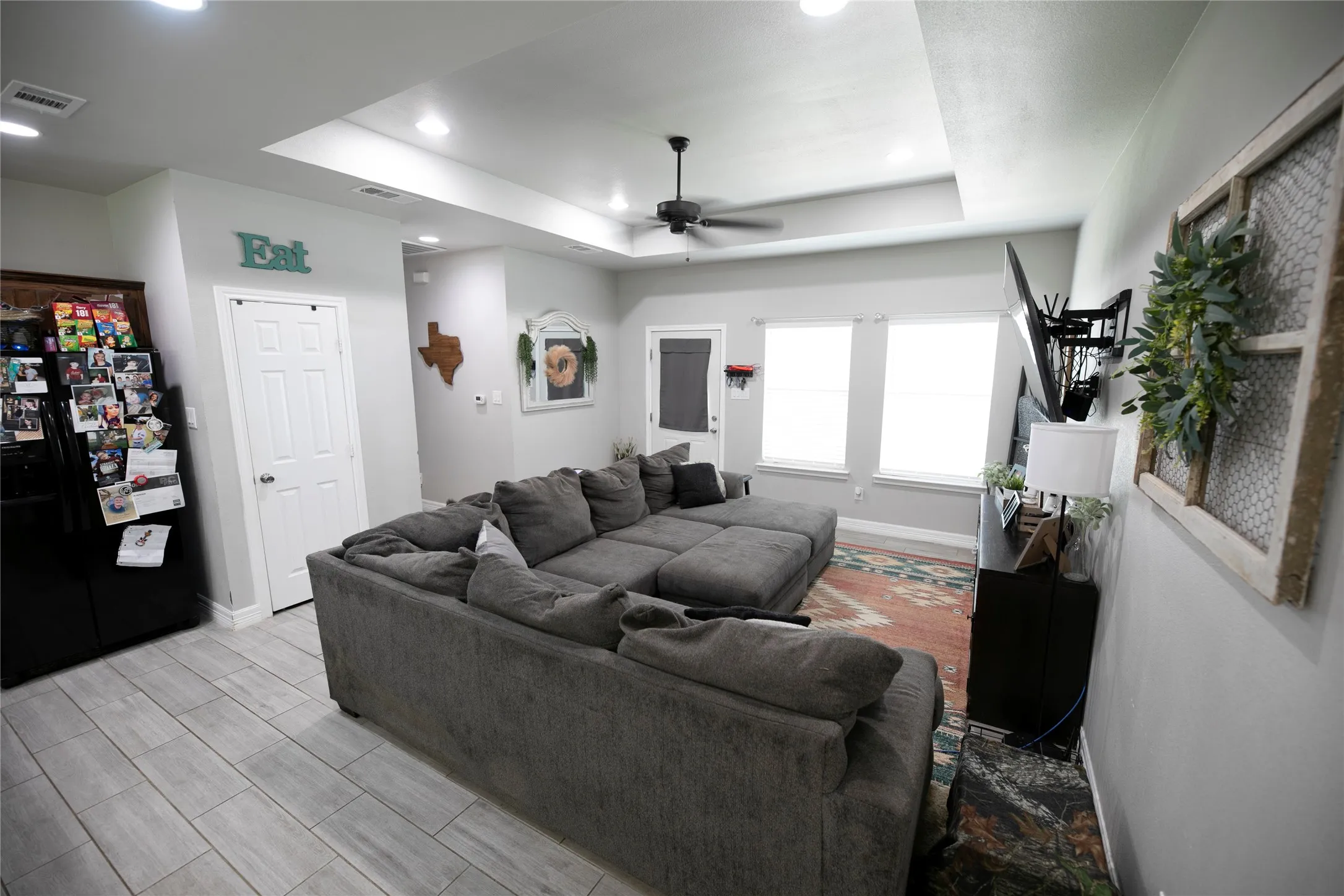 Open-concept living area featuring a tray ceiling with recessed lighting, a ceiling fan, and light wood-finish plank flooring