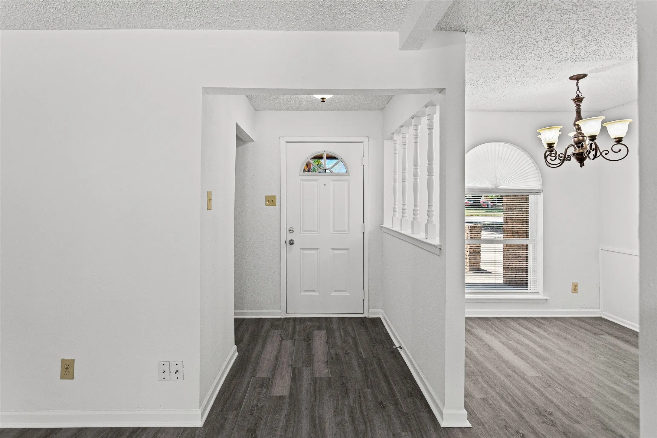 Entryway featuring wood-finish flooring and a decorative half-wall with spindles