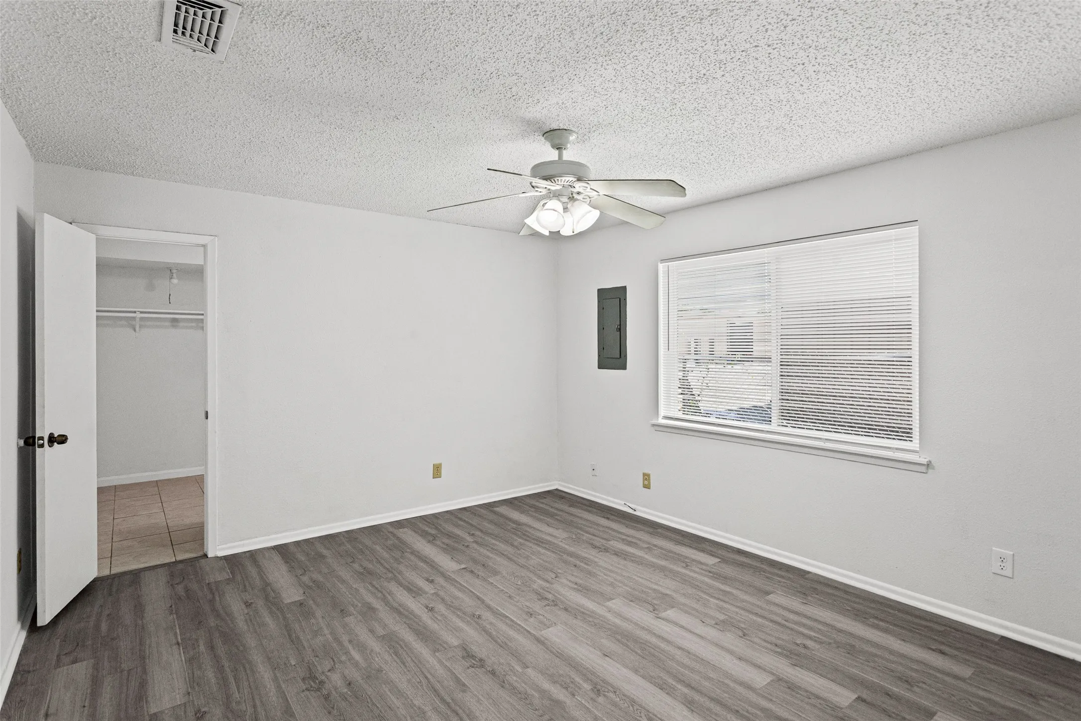 Spacious room featuring wood-finish flooring and a ceiling fan