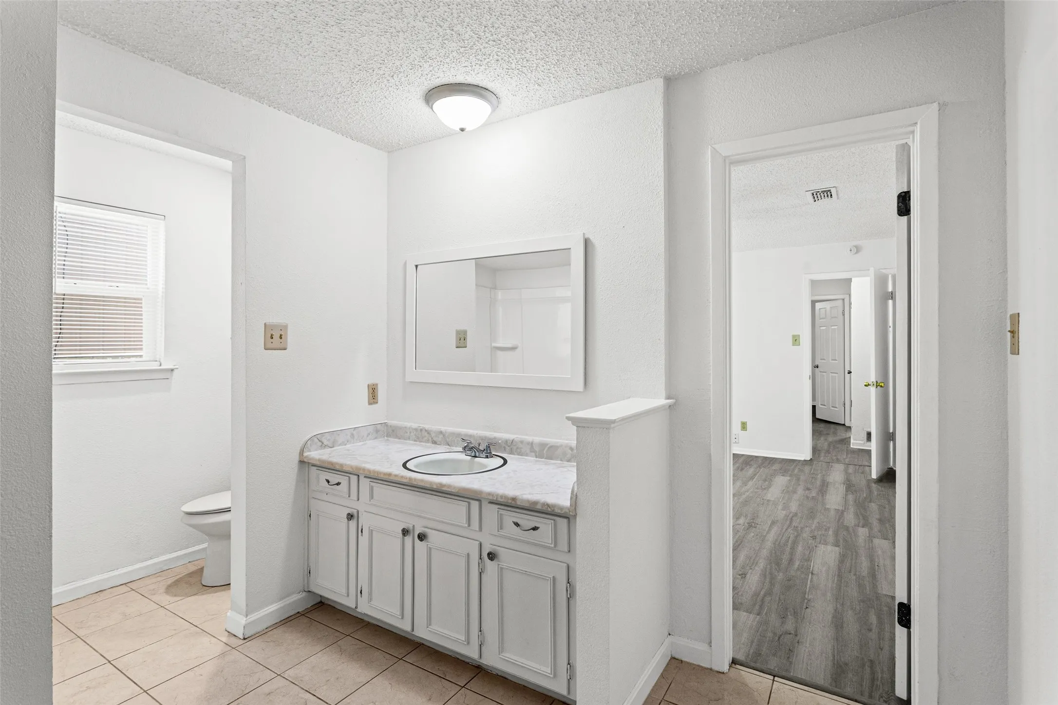 Vanity with a light-toned countertop and white cabinetry