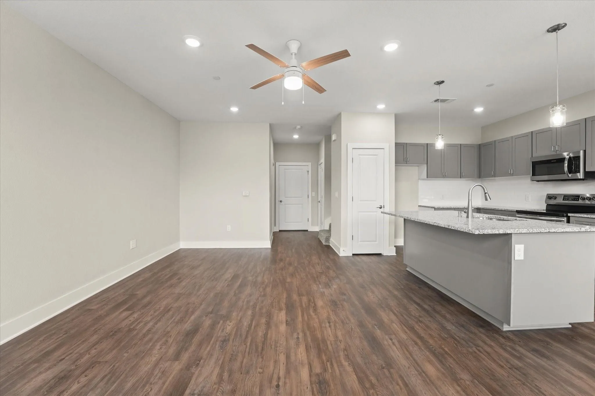 Open-concept living area featuring wood-finish flooring, recessed lighting, and a ceiling fan