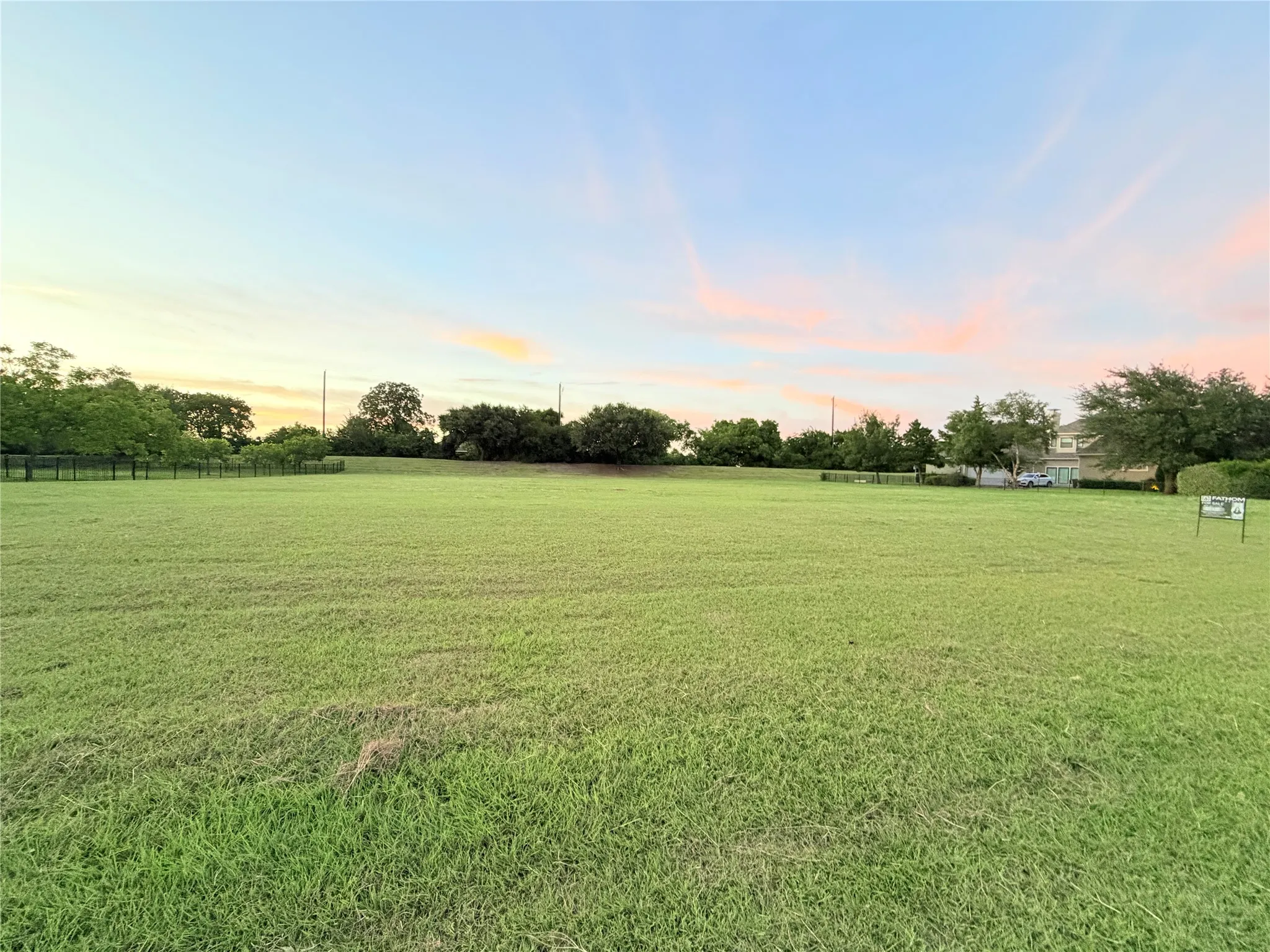 Expansive green space featuring a large, level grassy field and distant tree lines