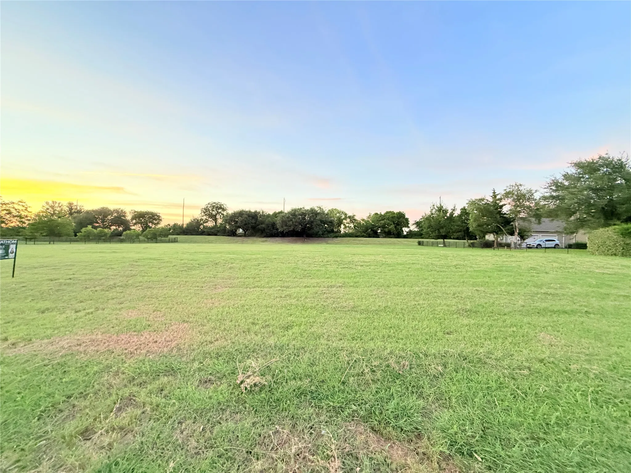 Expansive green space featuring a level terrain and natural tree line