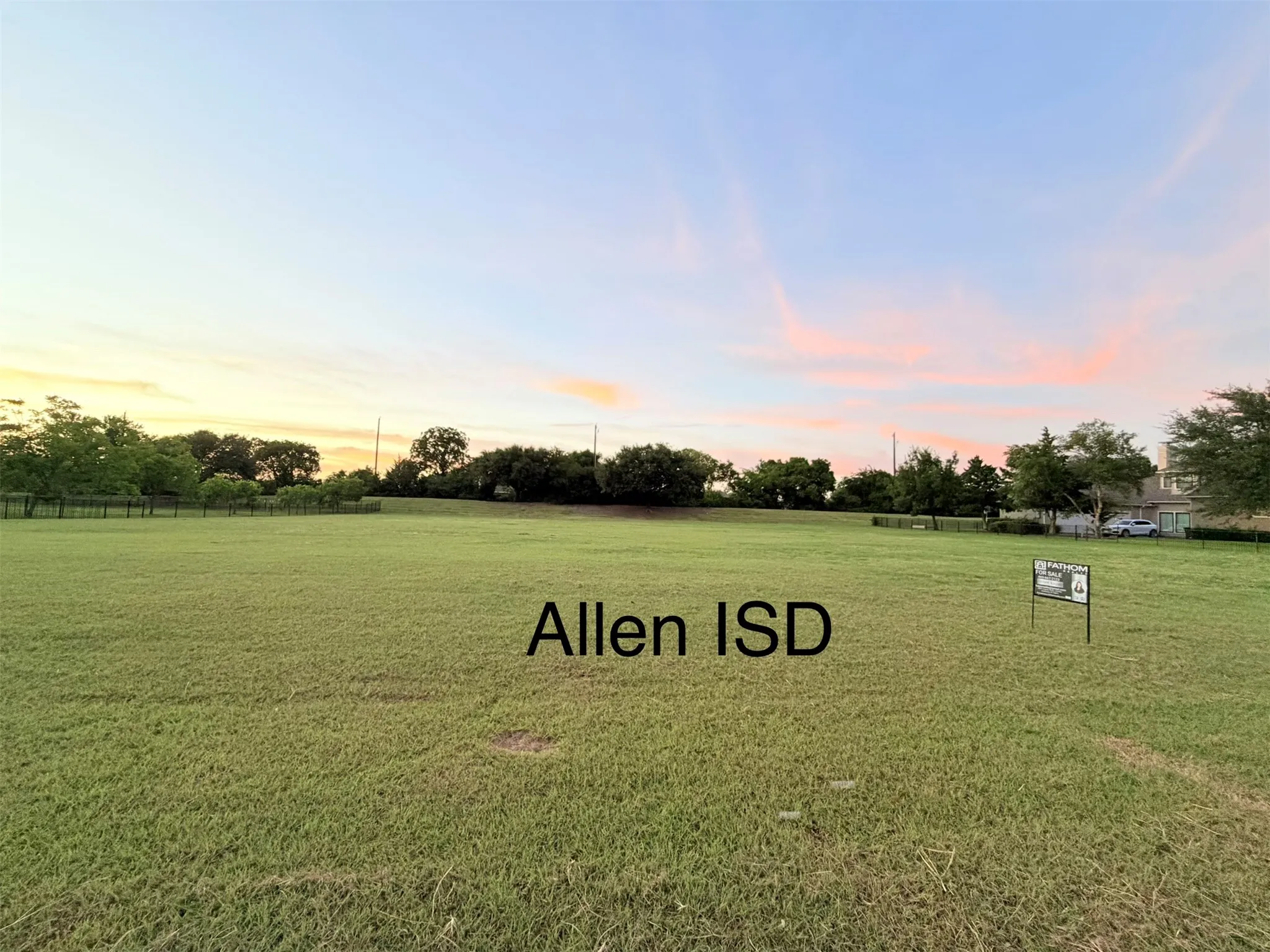 Expansive grass lot featuring a distant tree line and a clear sky