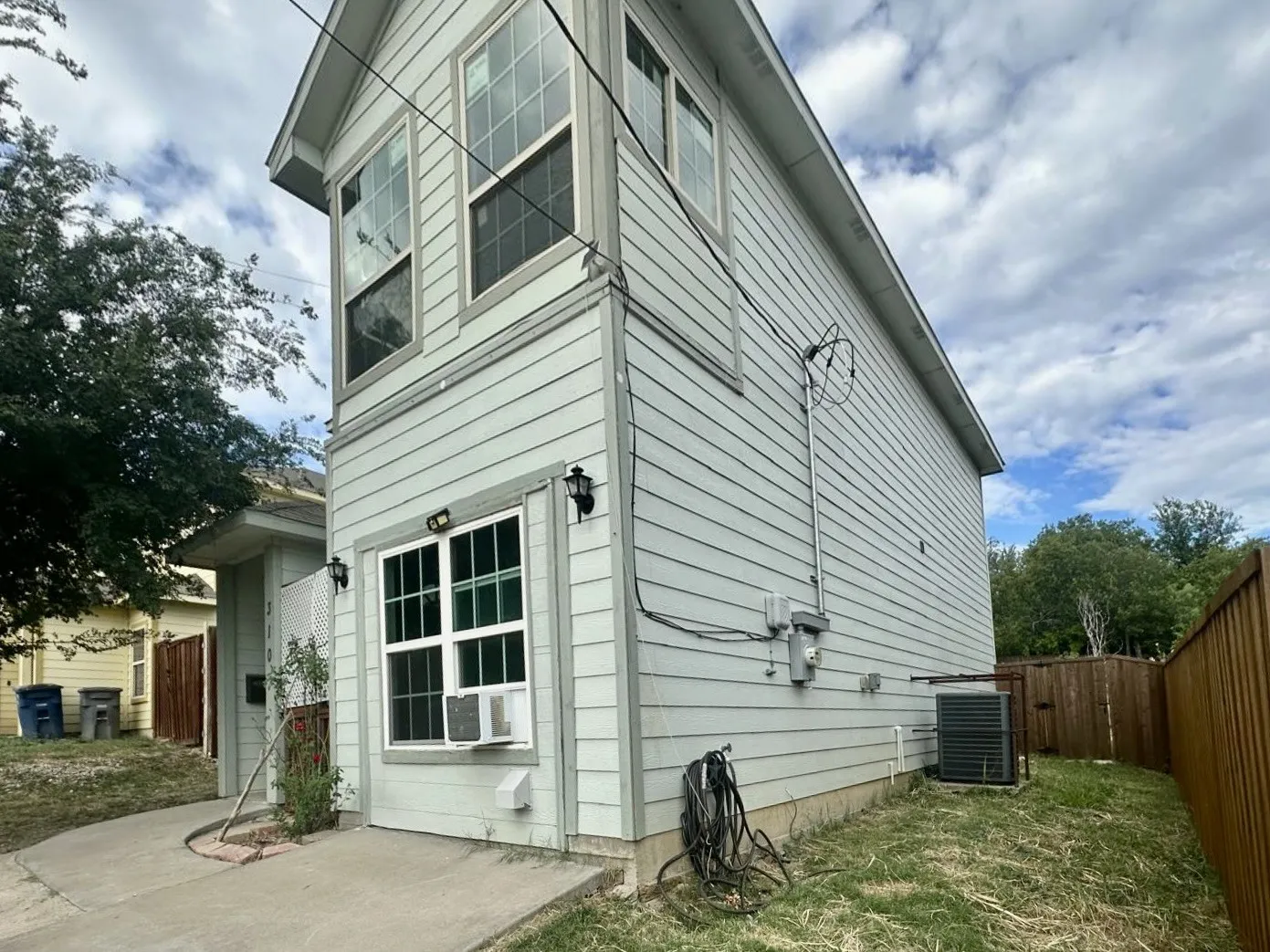 Two-story exterior with light-colored horizontal siding and enclosed balcony with multiple windows
