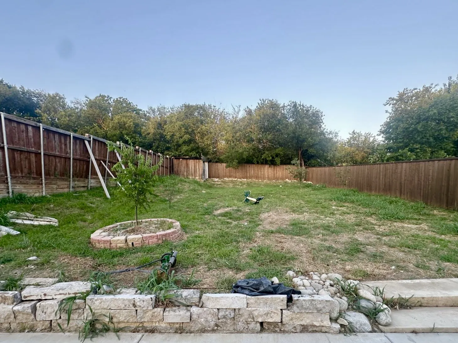 Expansive backyard featuring a stone retaining wall, partial wood fencing