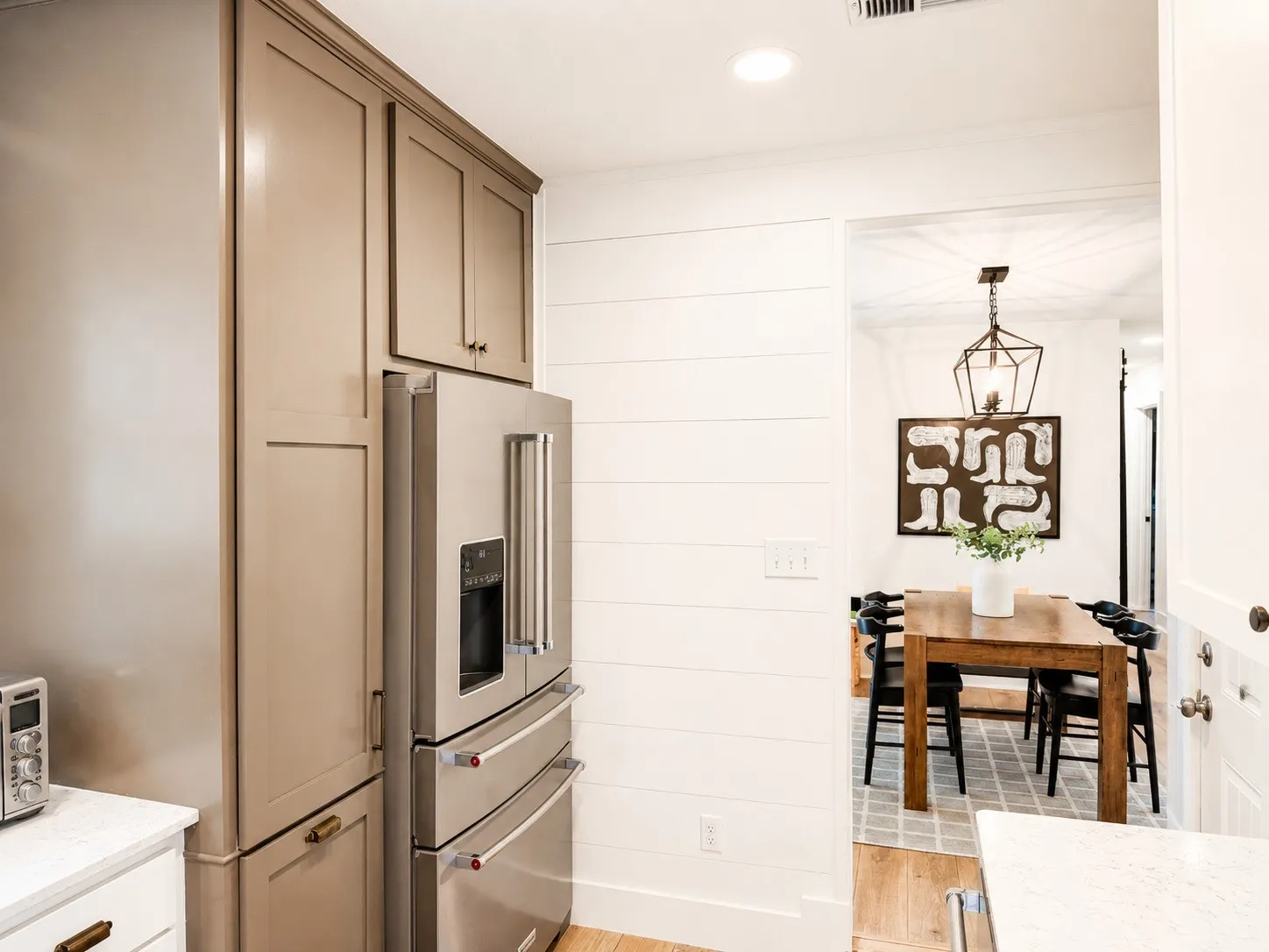 Modern kitchen featuring full-height cabinetry, stainless steel refrigerator, and shiplap paneling