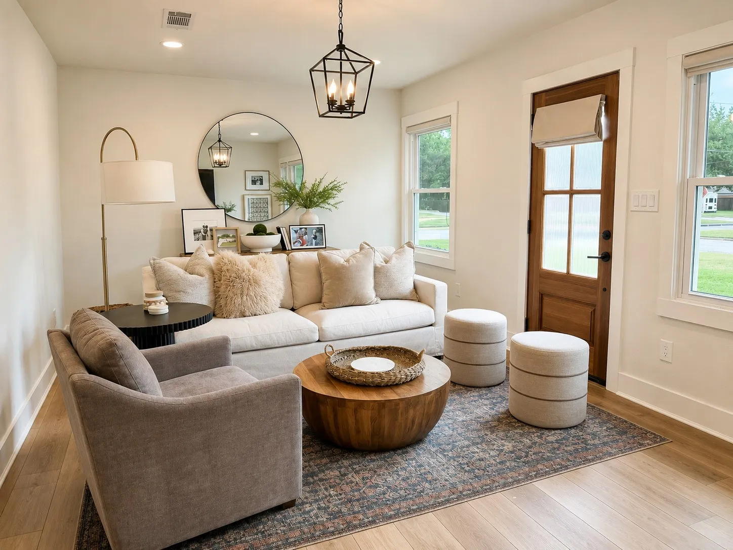 Living area featuring wood-finish flooring, a wood-panel entry door with glass panes, and multiple windows with white trim