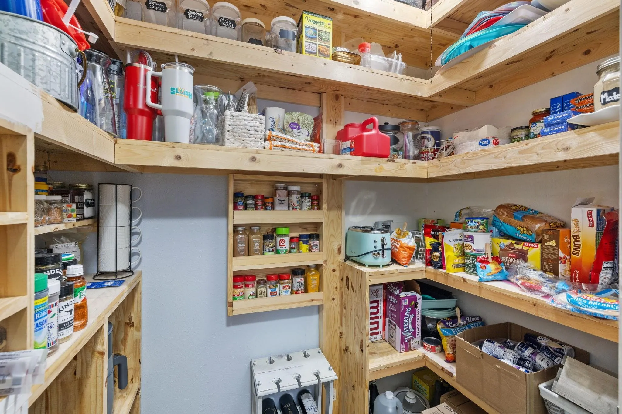 Custom pantry featuring extensive wood shelving, integrated spice racks, corner shelving units, and ample storage solutions