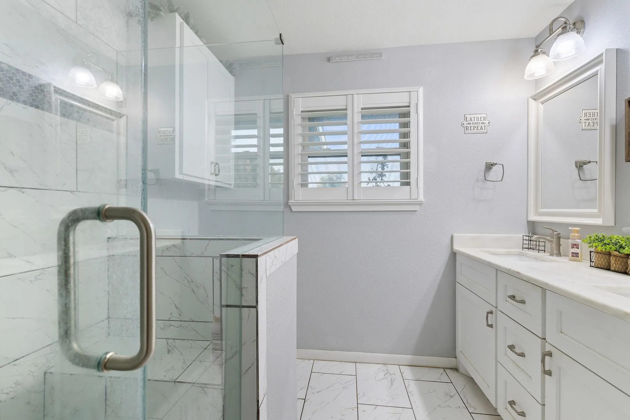 Guest Bathroom featuring a glass-enclosed shower with tile surround, white shaker-style vanity with stone countertop, polished nickel fixtures, and plantation shutters