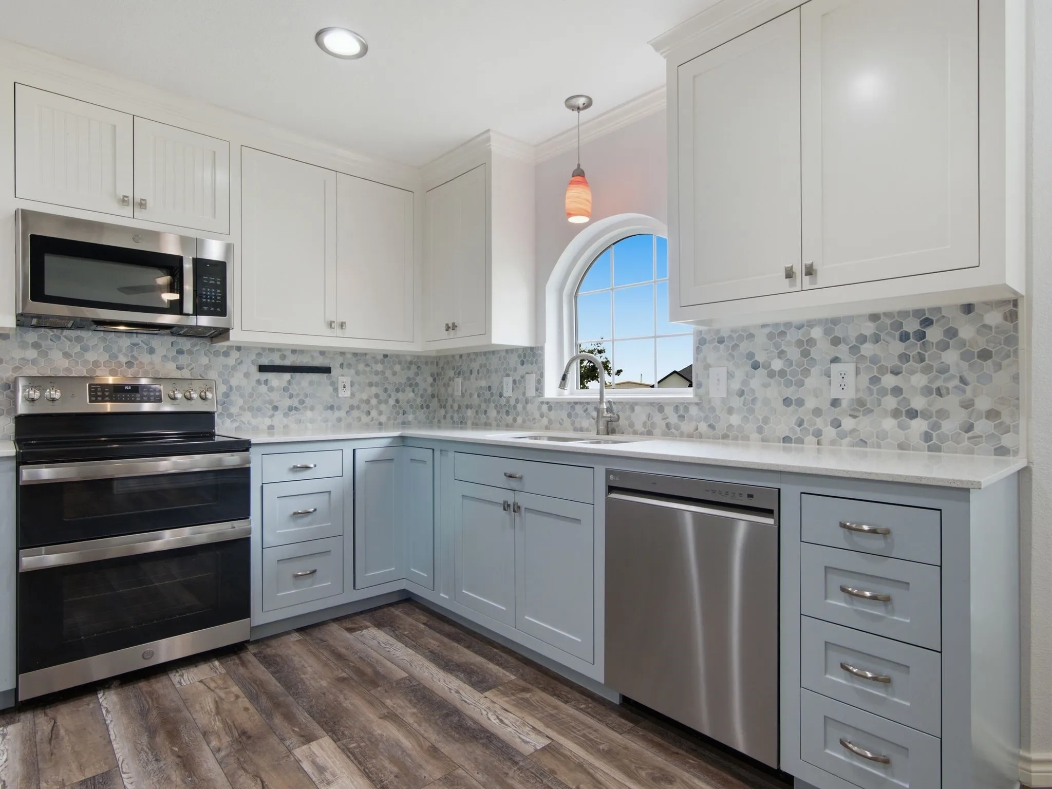 Modern kitchen featuring two-tone cabinetry, stainless steel appliances, and wood-finish flooring