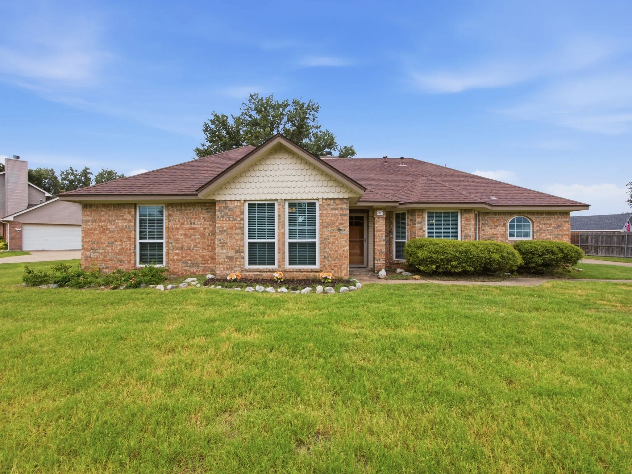 Brick exterior with a brown shingle roof and a green lawn