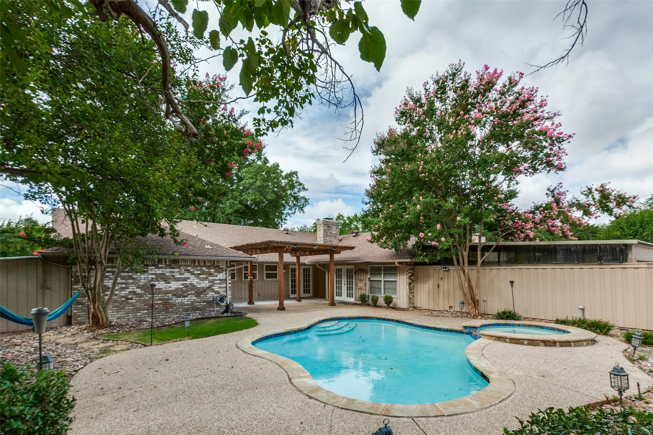 Backyard oasis featuring a freeform pool, integrated spa, and expansive concrete patio