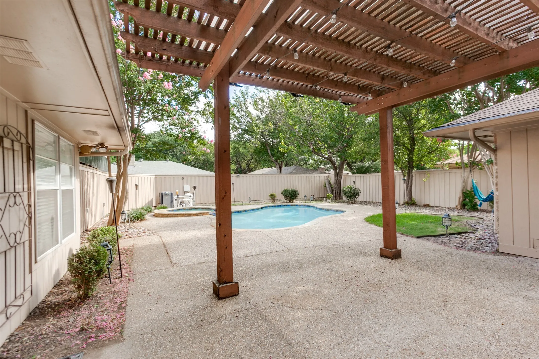 Backyard oasis featuring a freeform swimming pool, integrated spa, and expansive aggregate concrete patio