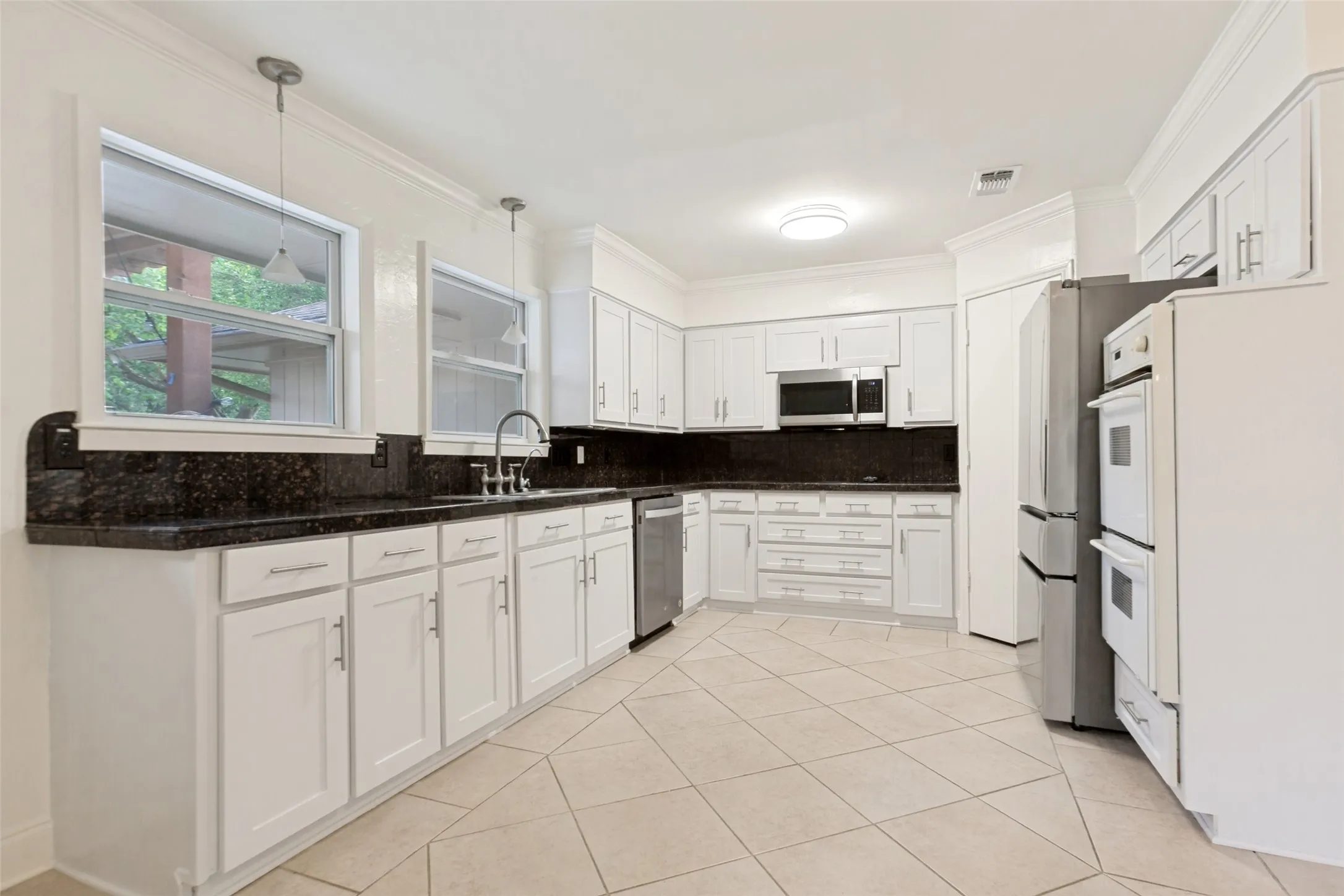 Kitchen featuring white cabinetry, dark speckled countertops, and an undermount sink with a gooseneck faucet