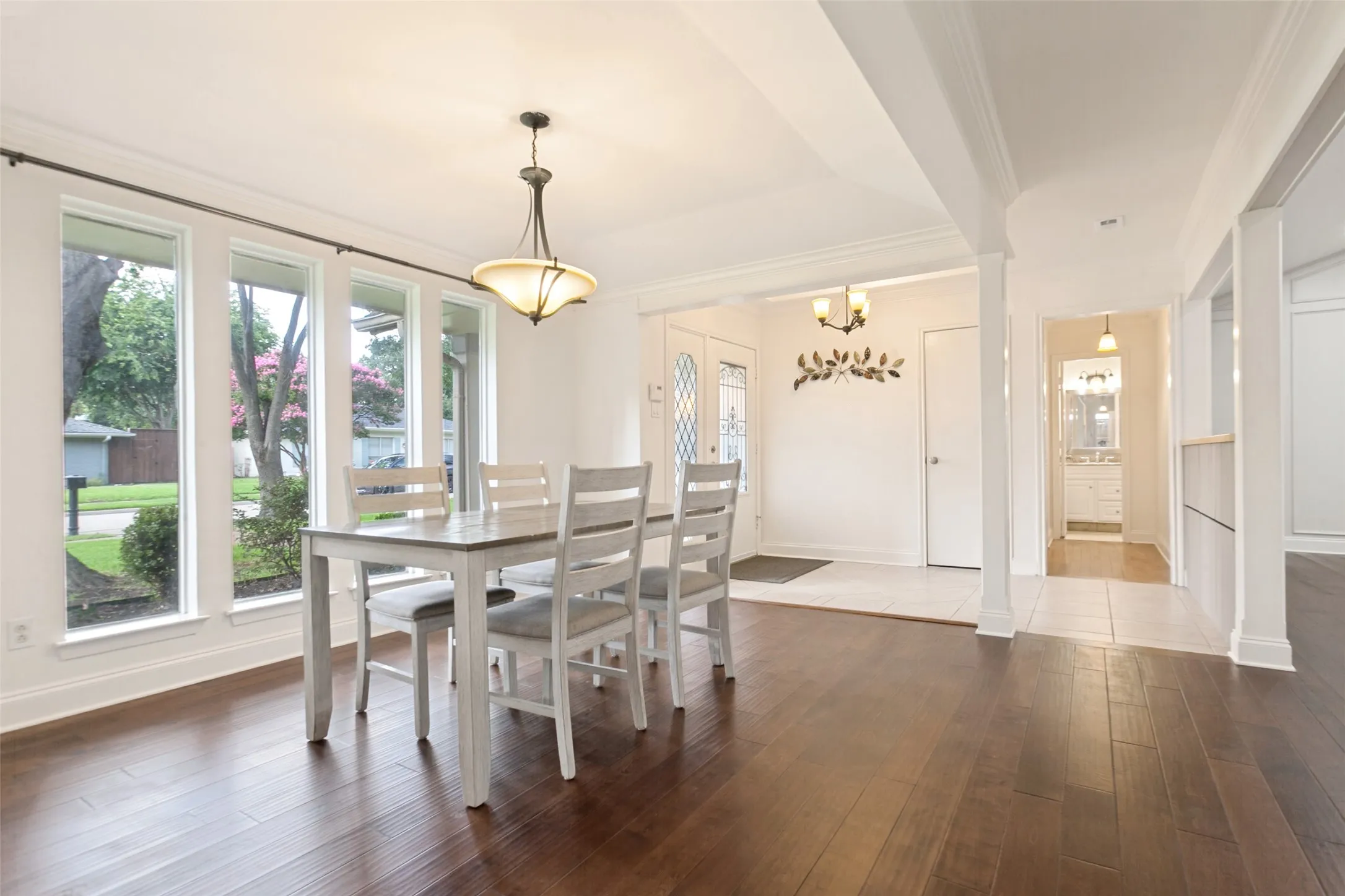 Spacious dining area featuring wood-finish flooring, a contemporary chandelier, and large windows providing ample natural light