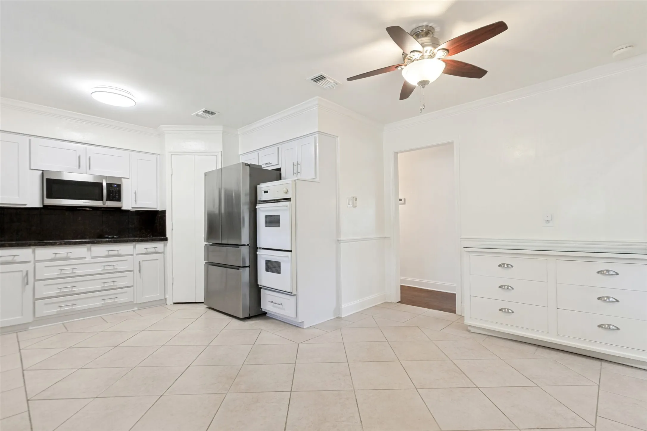 Kitchen featuring white cabinetry with dark countertops, stainless steel appliances, and diagonal tile flooring