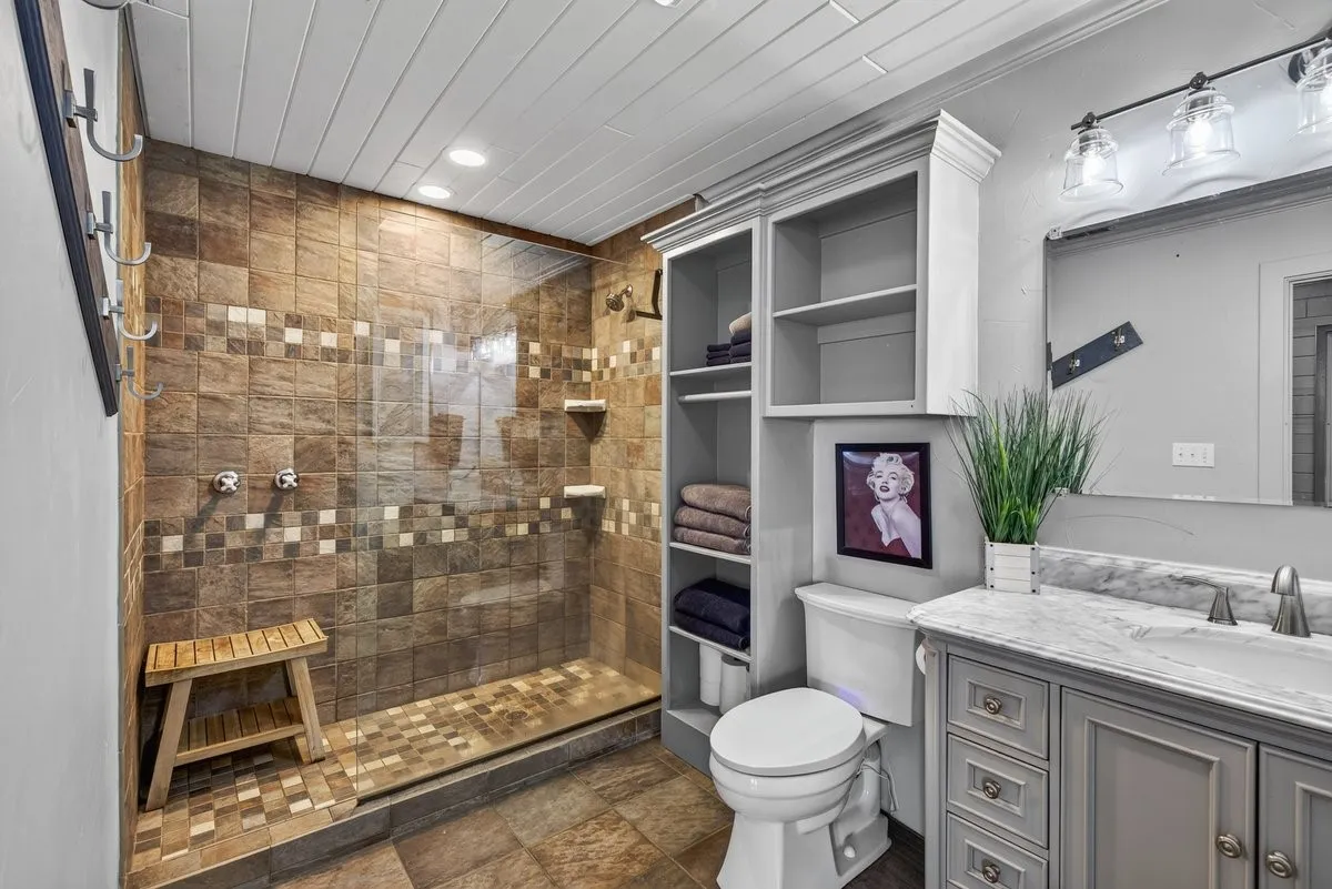 Warm natural stone style shower in primary bedroom.