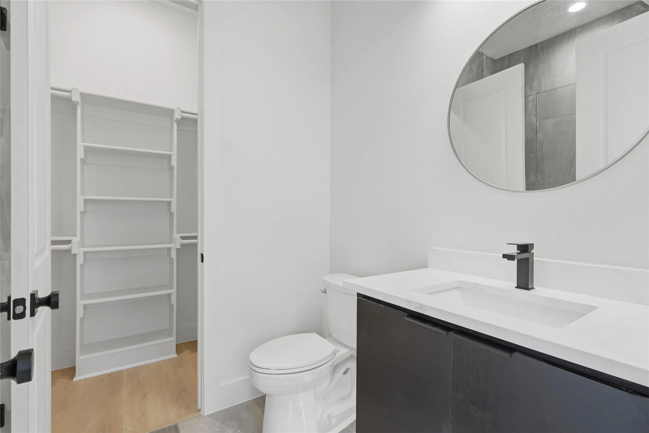 Modern vanity with a rectangular integrated sink, matte black faucet, and round mirror