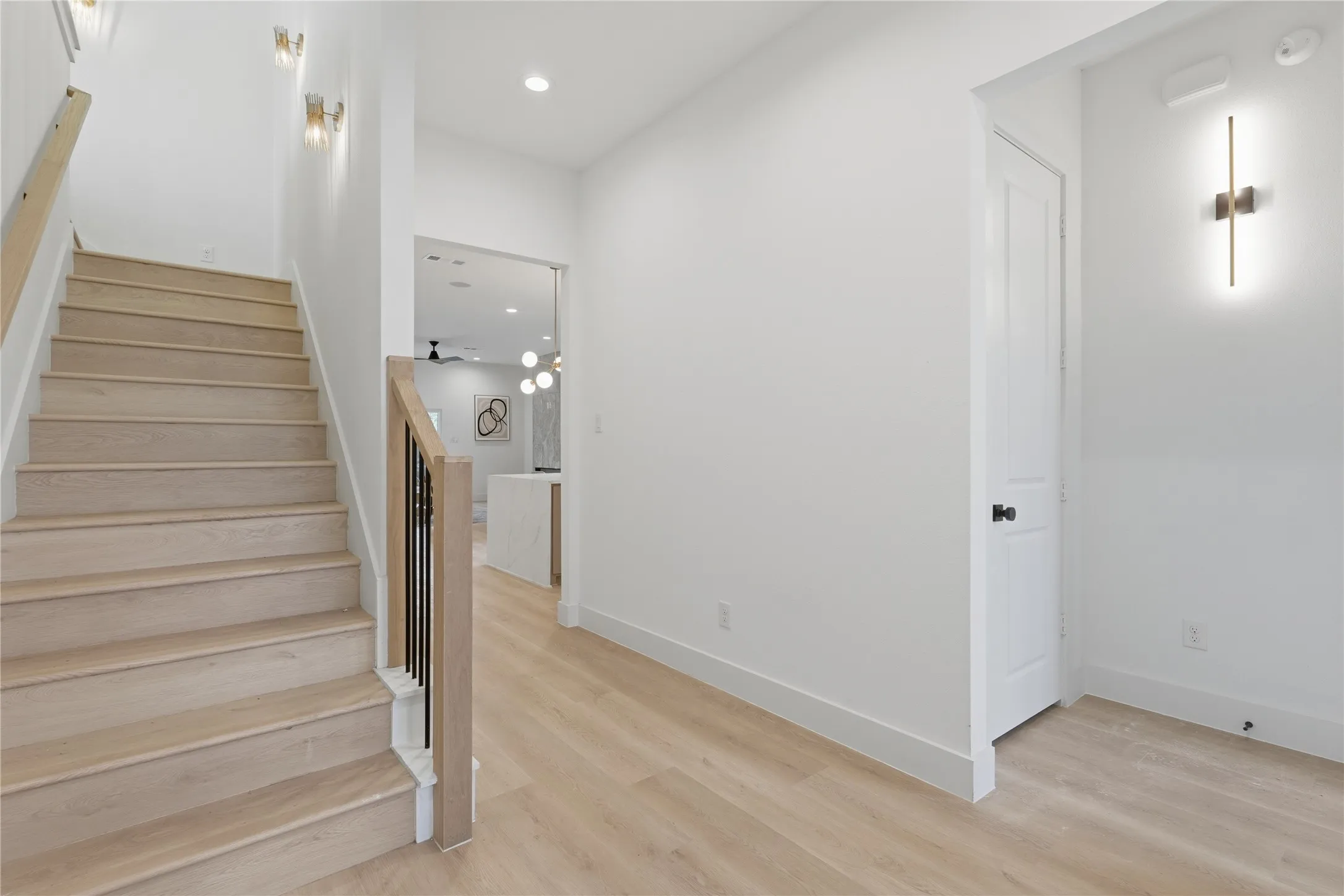 Staircase with light wood-finish treads and risers, black metal balusters, and a light wood-finish handrail