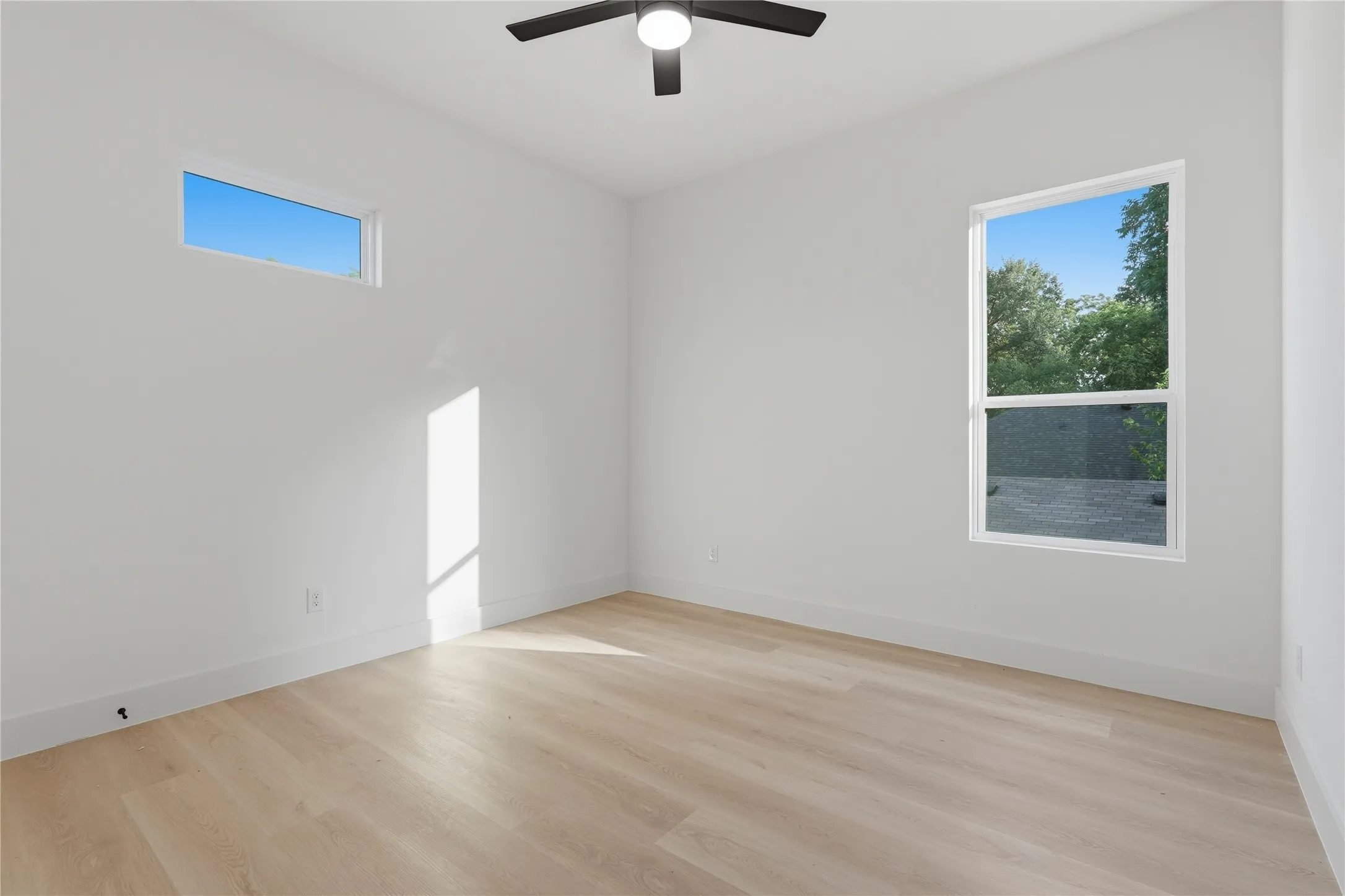 Bright interior space featuring light wood-finish flooring, white baseboards, and white walls