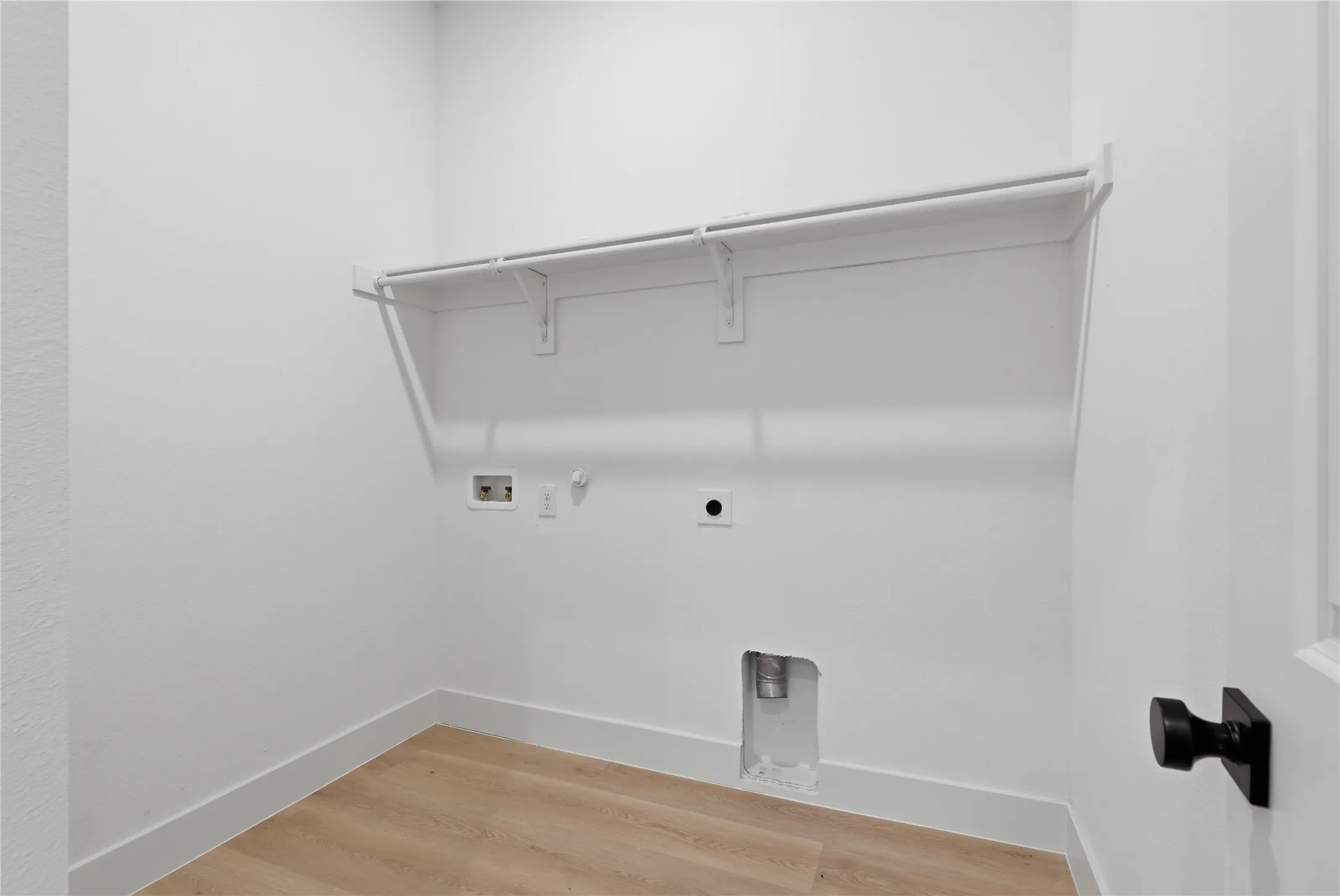 Utility room with wood-finish flooring, white walls, and baseboards