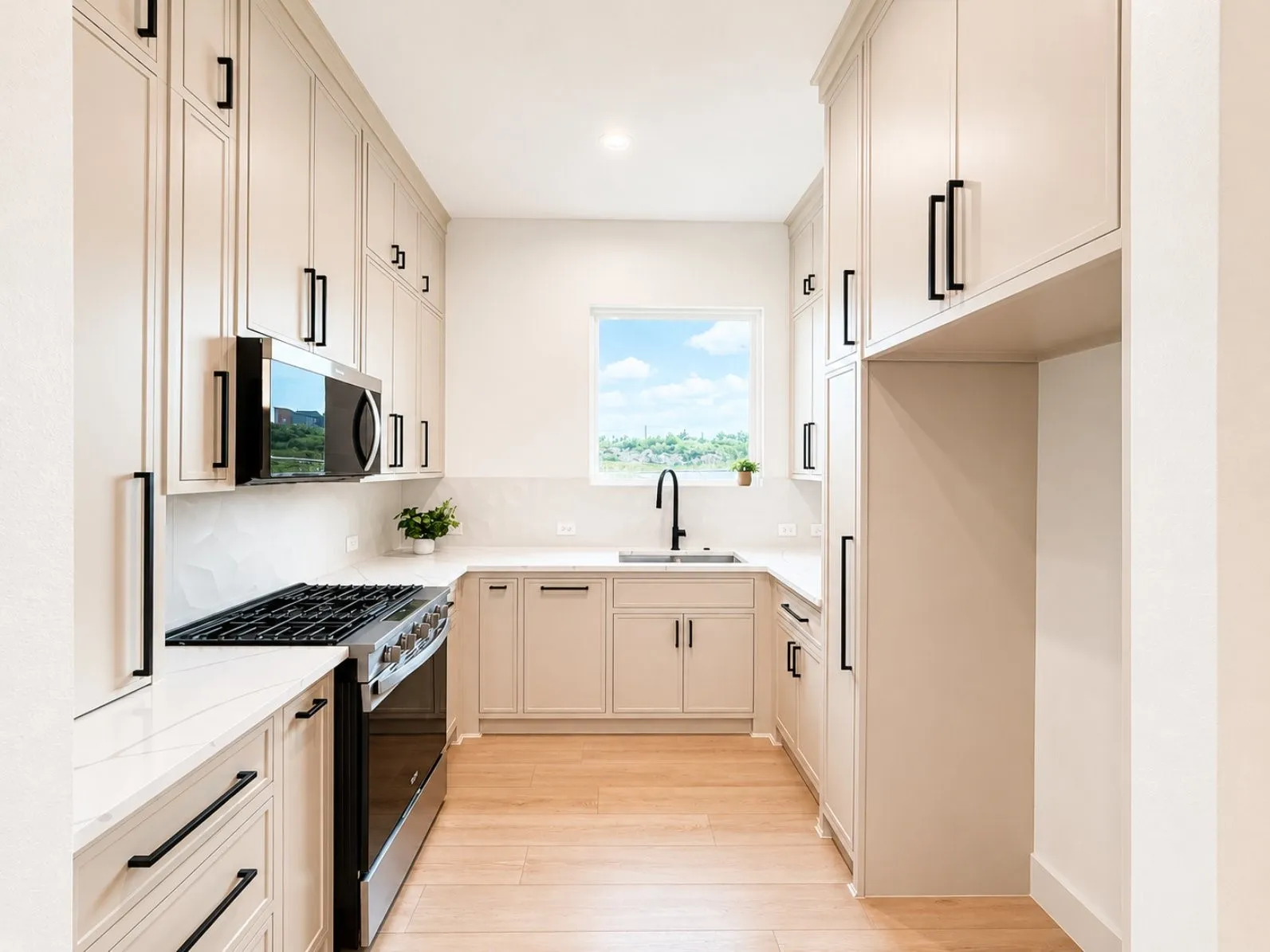 Contemporary guest quarter kitchen featuring extensive light-toned cabinetry with matte black hardware