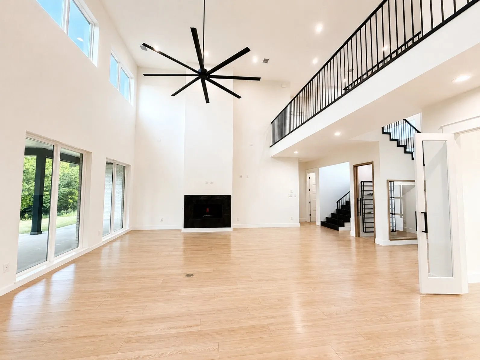 Spacious living area featuring high ceilings, light wood-finish flooring, and a contemporary fireplace with a dark surround