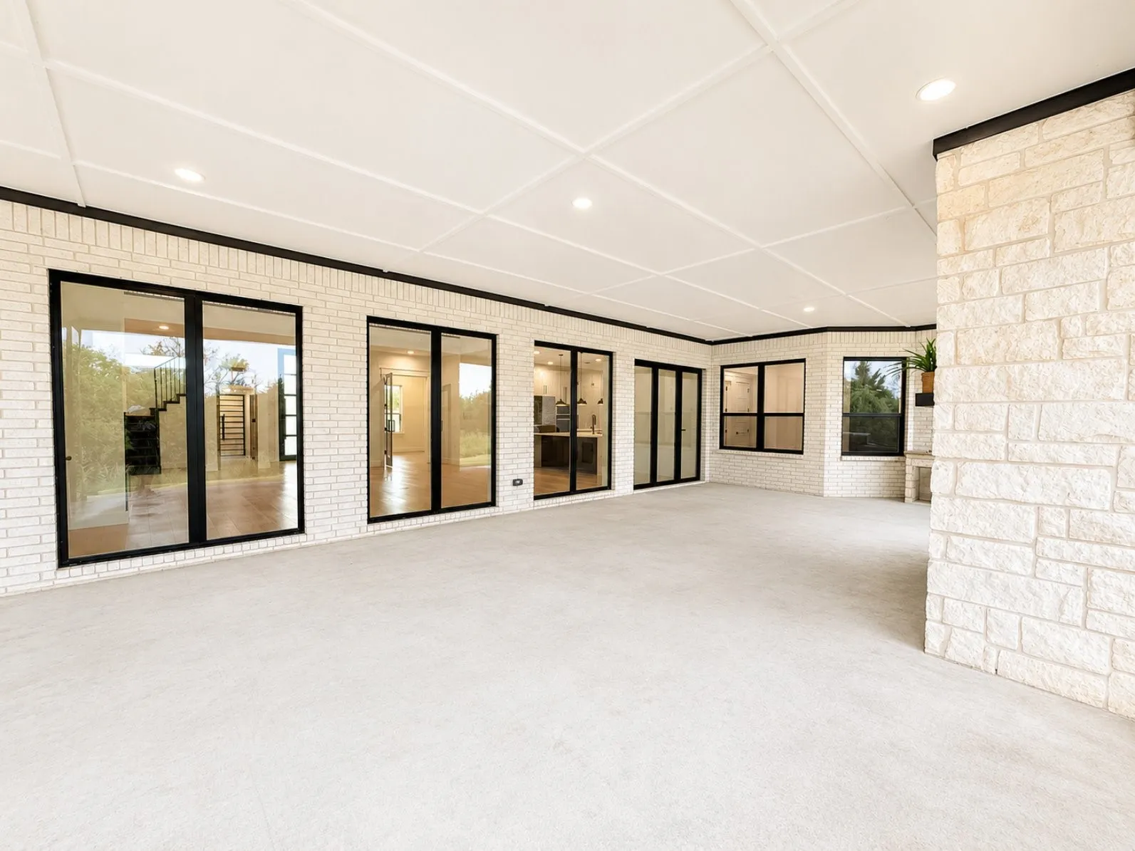 Spacious covered patio featuring white brick exterior walls and a stone fireplace
