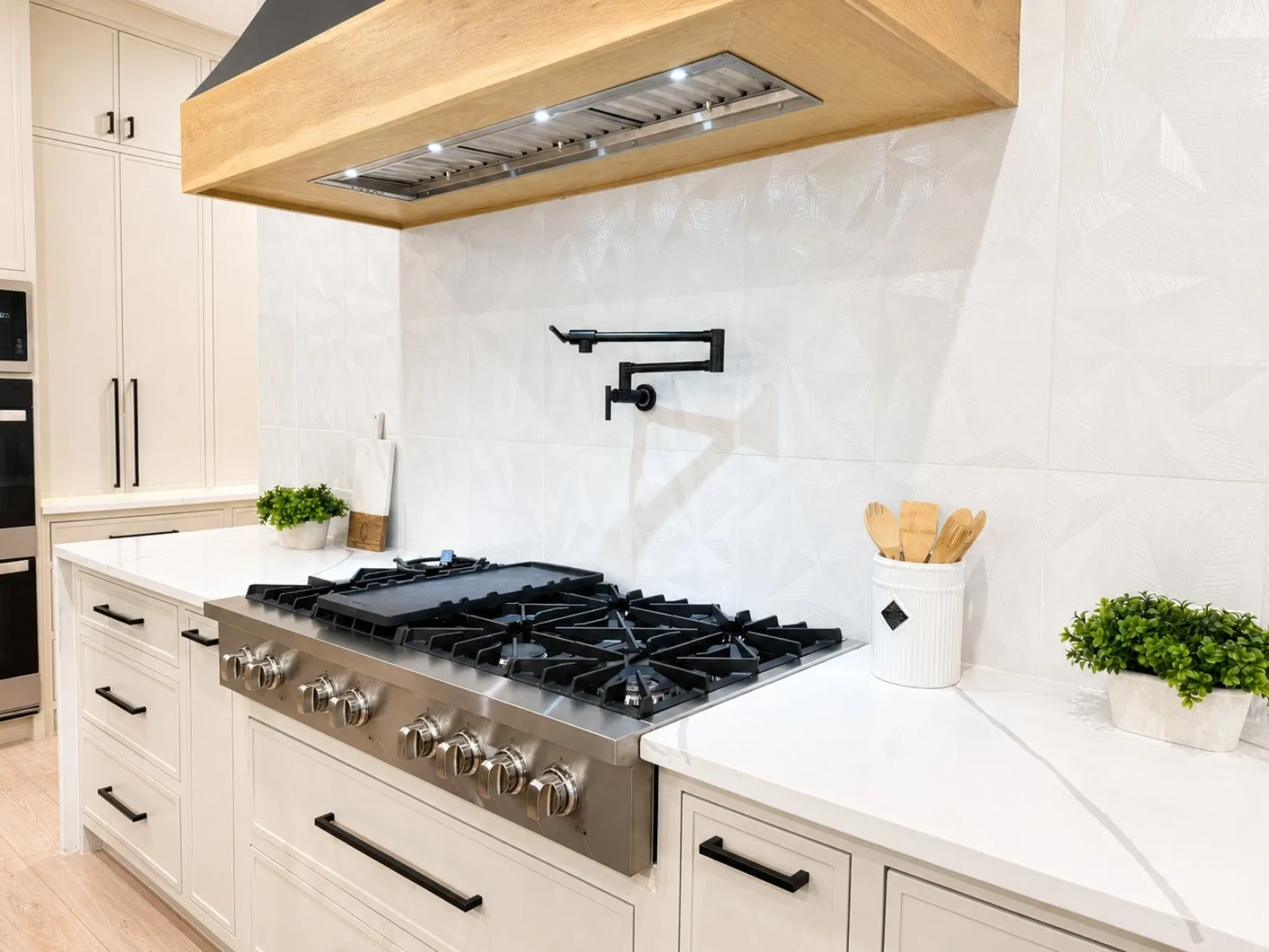 Professional-grade gas range with a pot filler, set against a geometric white tile backsplash