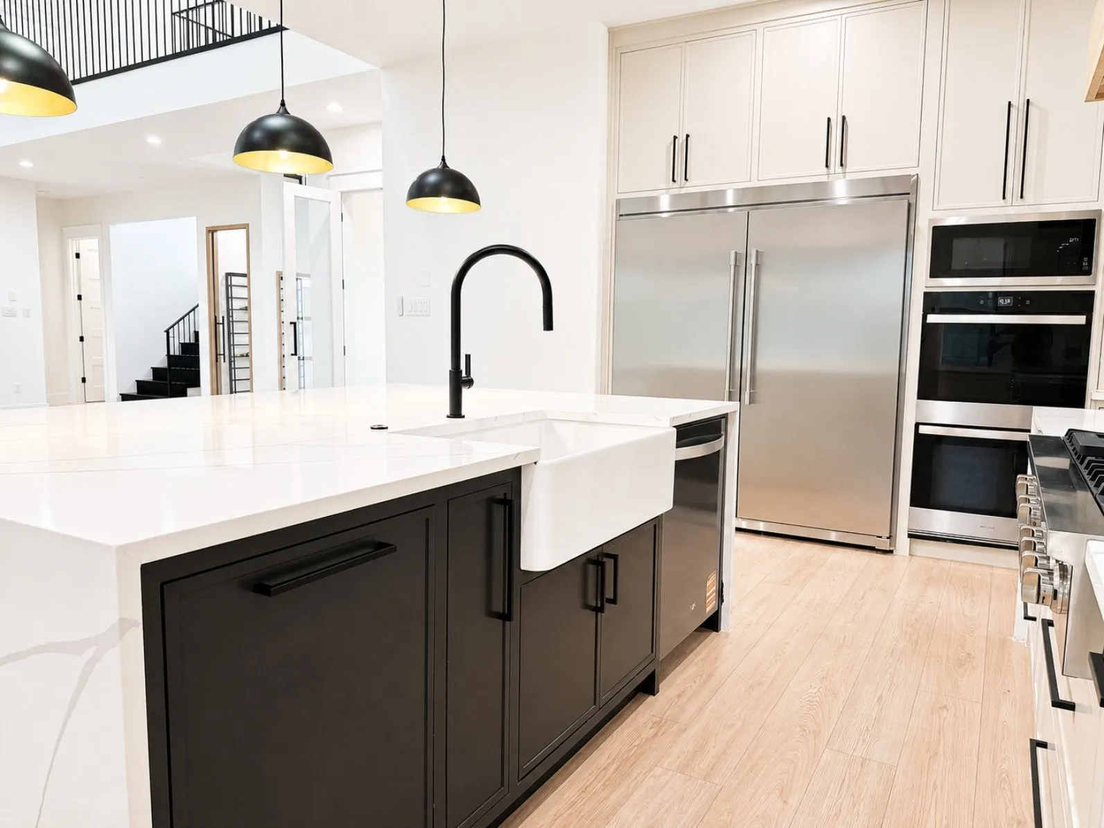 Modern kitchen featuring a large central island with a white farmhouse sink and matte black gooseneck faucet