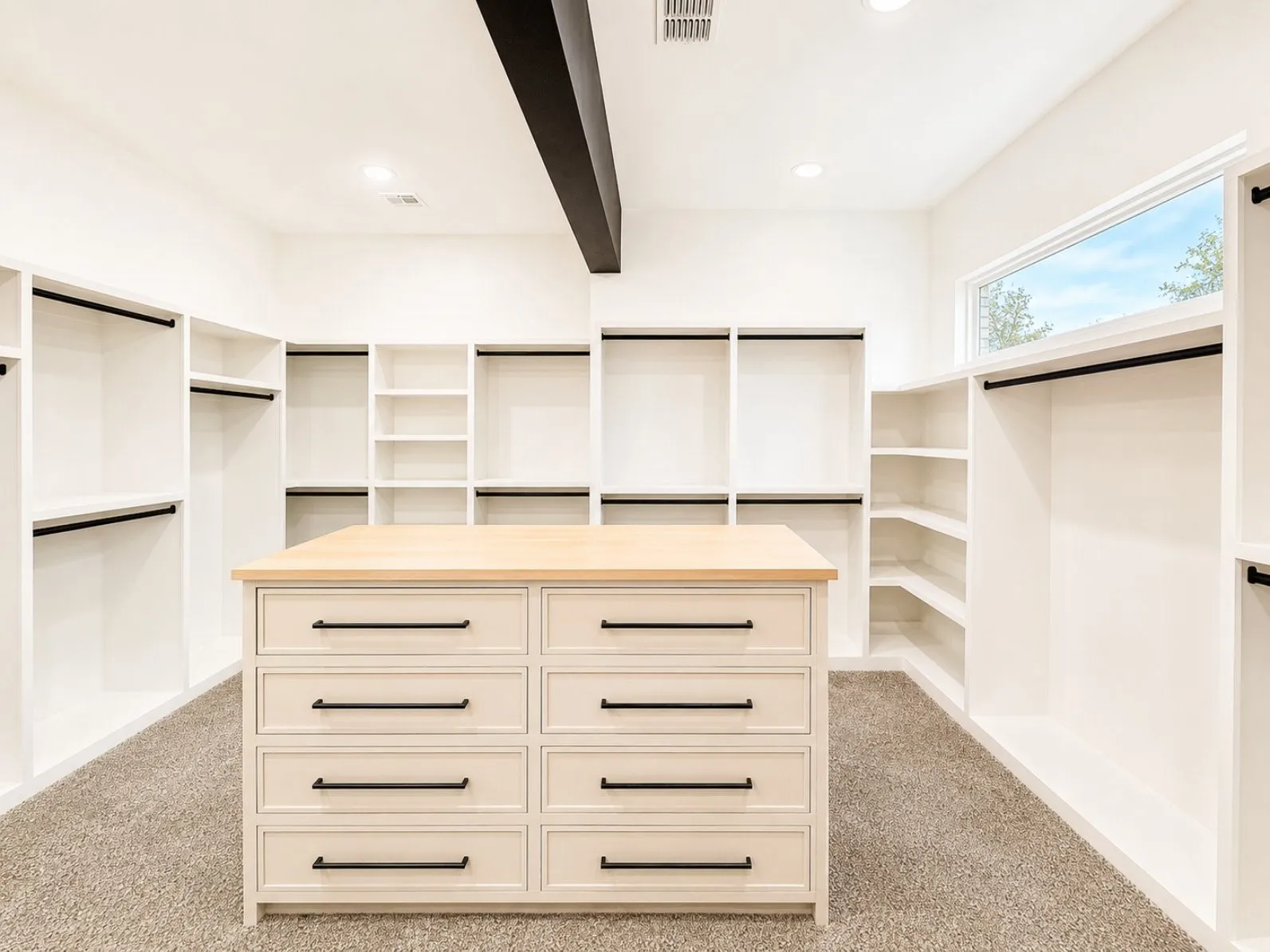 Spacious custom closet featuring a central island with natural wood-finish countertop and drawer storage