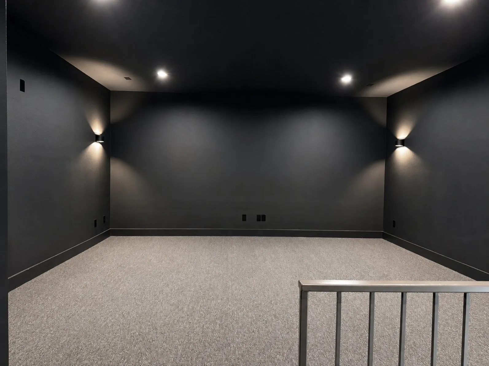 Spacious media room featuring dark walls, recessed ceiling lighting, and pre-wired for sound system and data