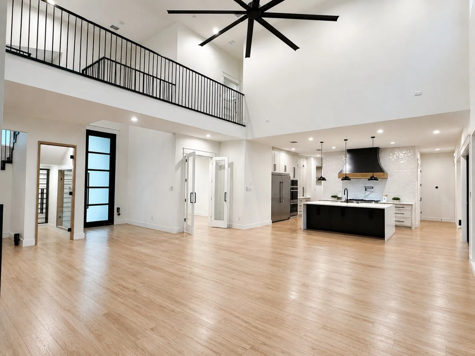 Spacious open-concept living area featuring light wood-finish flooring and a high vaulted ceiling