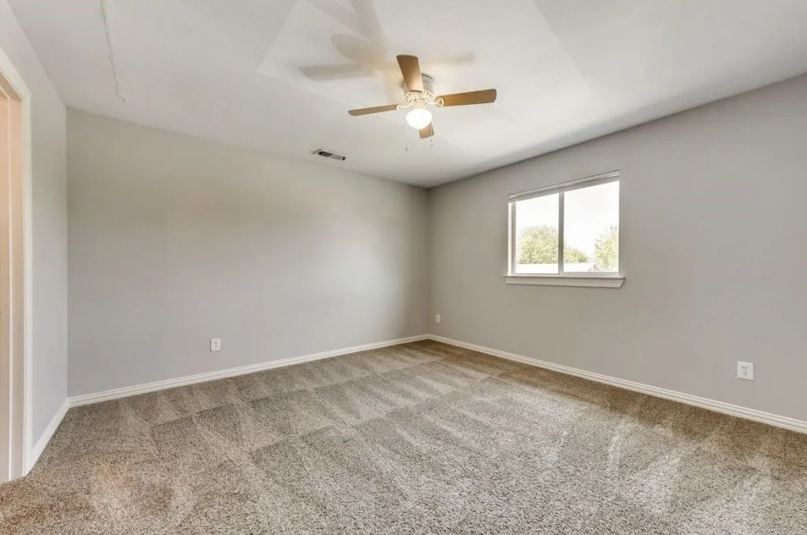 Carpeted room featuring a ceiling fan with integrated lighting, a double-hung window, and neutral wall paint