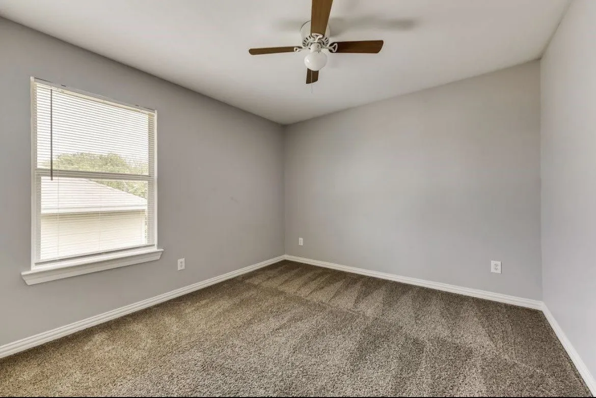Carpeted room with a ceiling fan, a single window featuring blinds, and neutral colored walls