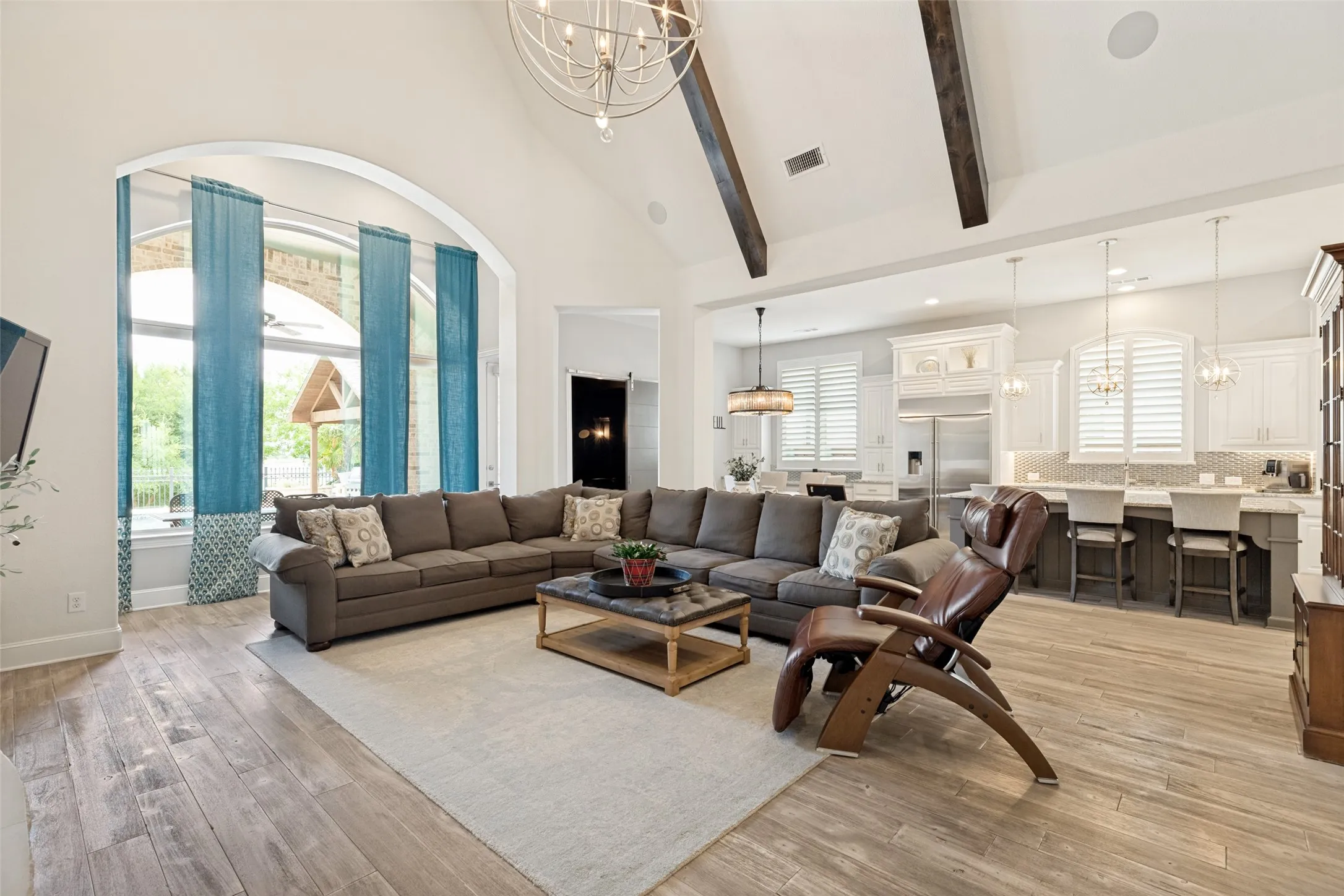 Another memorable feature of the home is the massive window set in a gallery just beyond an arched casement.  The view of the outdoor amenities and the greenery and lake beyond is stunning.  There is plenty of space for furniture choices, and the LVP flooring is a nice backdrop for a pretty rug to anchor the room.