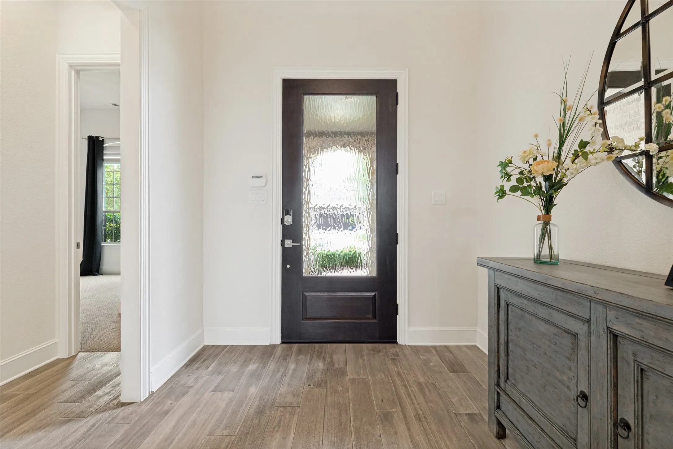 The handsome eight foot front door with a large obscure glass panel welcomes guests to the home, and a window above the door adds additional natural light.  Handsome premium Luxury Vinyl Plank flooring begin in the entry and set expectations of the exciting features to come.