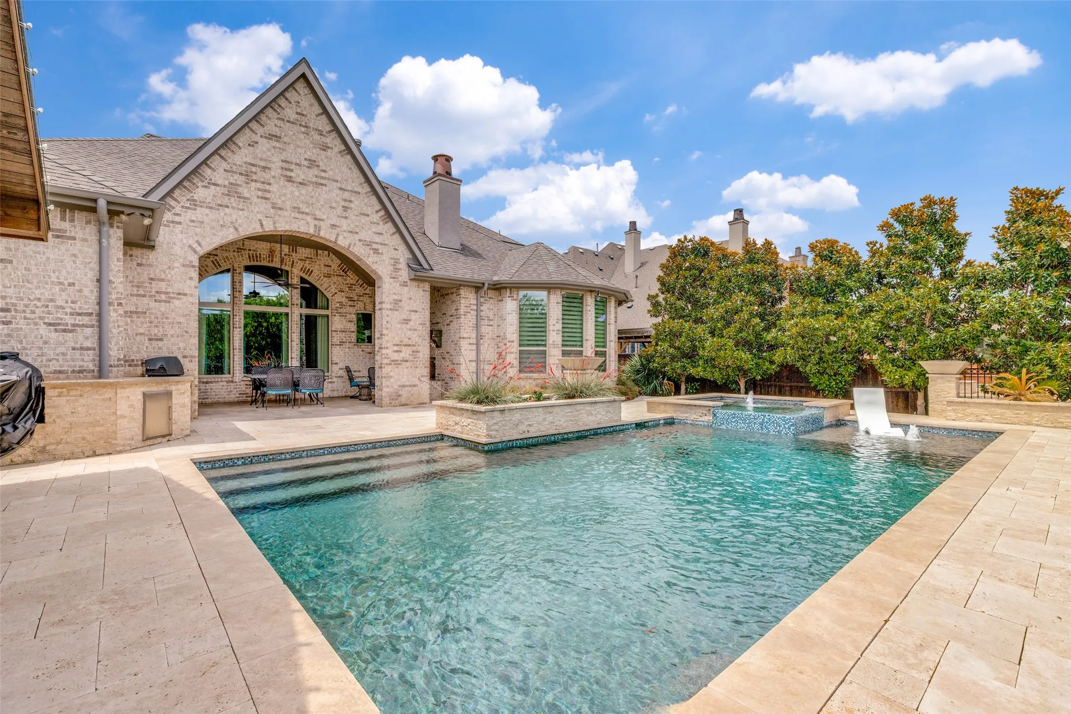 No need to wait for a pool to be built... you can bring the floats and drive right in the day you get the keys!  This sparkling pebble tec plastered pool is as beautiful as it is fun.  Travertine decking is on the patio and surrounds the pool.  Raised planter beds add attractive landscaping and two raised fire bowls light up the night.