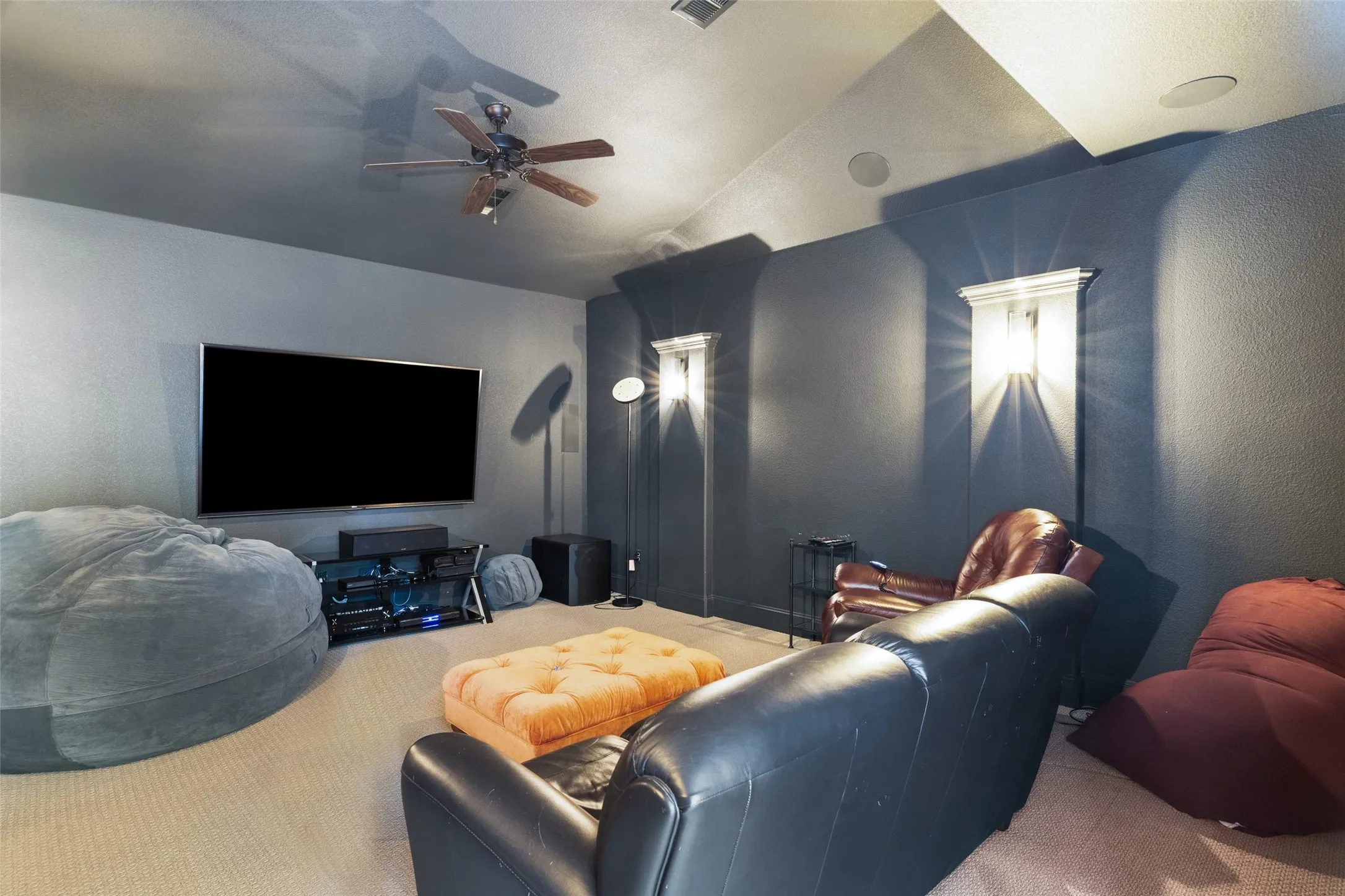 The downstairs media room is another popular feature of the floor plan.  Pillars with sconces and dark paint provide a theater effect.  Speakers are in the ceiling and durable carpet is on the floor.  Bring the popcorn and your own media equipment and enjoy a family movie night or favorite sporting events.