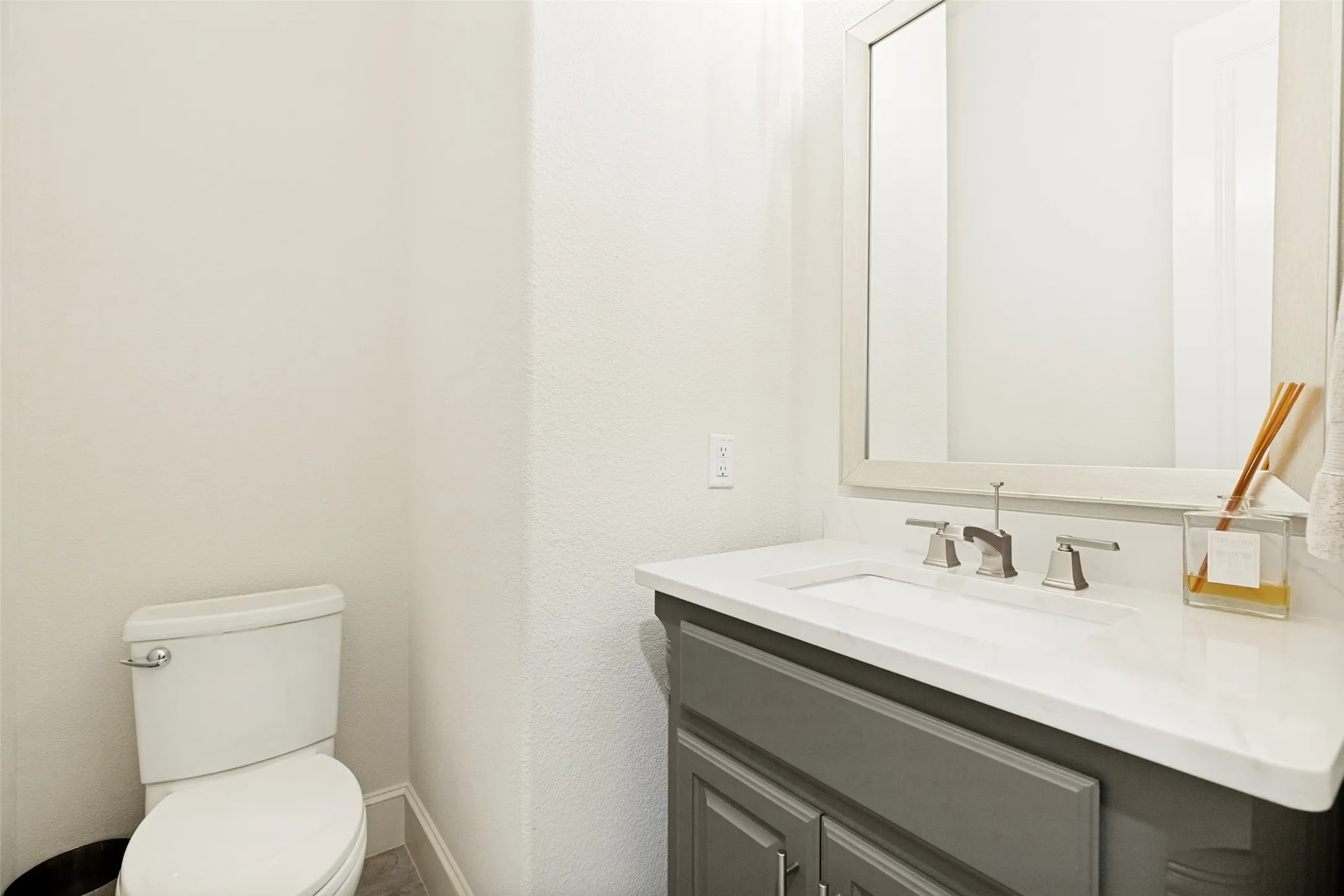 Another popular feature in this home is the two half baths - one downstairs and one upstairs.  This downstairs powder bath incudes a taupe painted vanity cabinet with a cream countertop and an undermount sink.  A metallic mirrow is above topped by a light fixture.