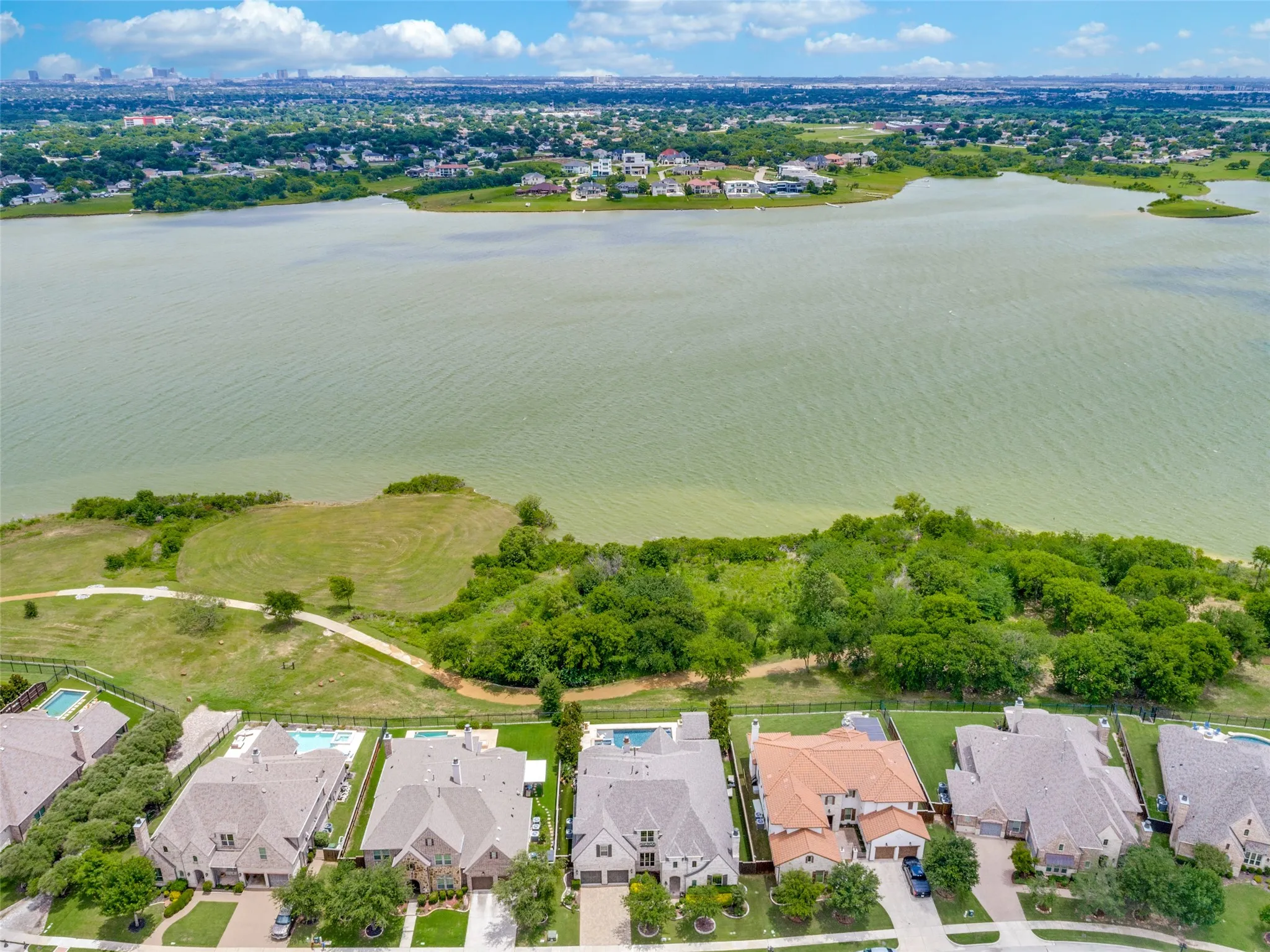 This ariel view shows the proximity of the home (in the middle to the left of the tile roof) to the lake.  A hiking trail meanders behind the iron fence and lakeshore is just beyond.  To the right, the trail that is part of the community trail system leads to the neighborhood kayak launching pad.