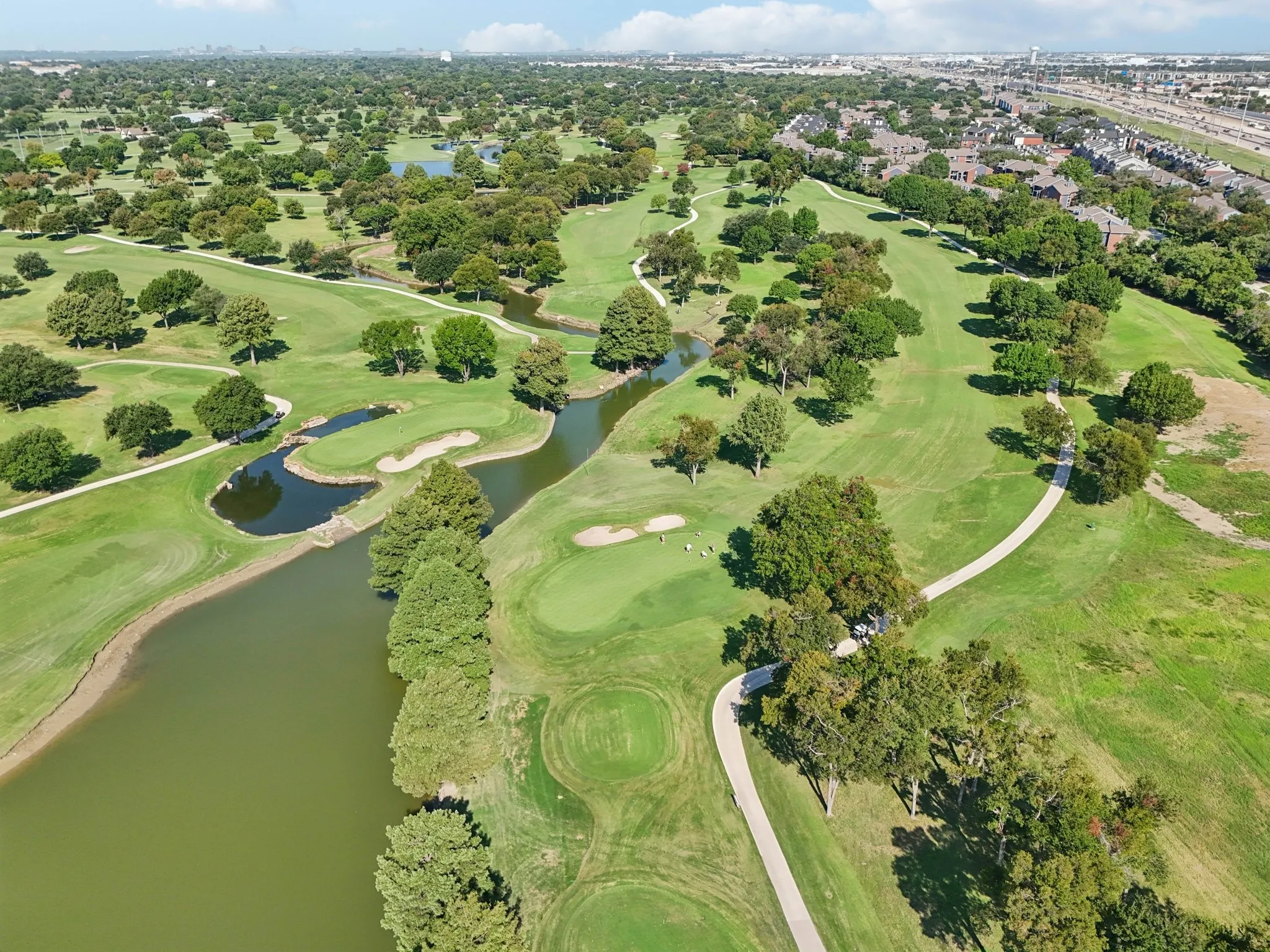 Expansive golf course featuring multiple greens, water features, sand traps, and paved cart paths